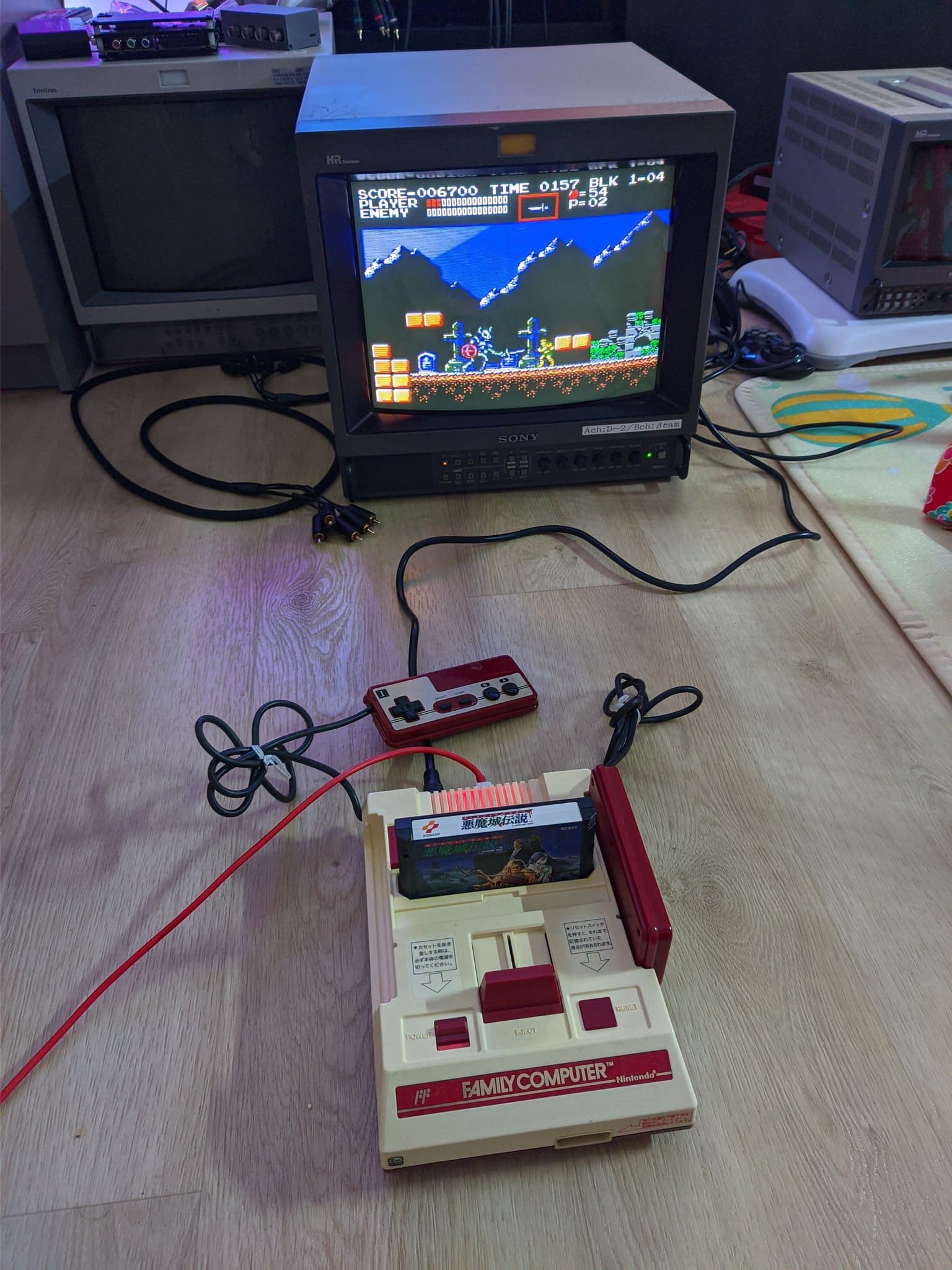 Repaired Nintendo Famicom running Castlevania III on a Sony CRT through its new composite output, with its wired controller and red cartridge in place on the floor.