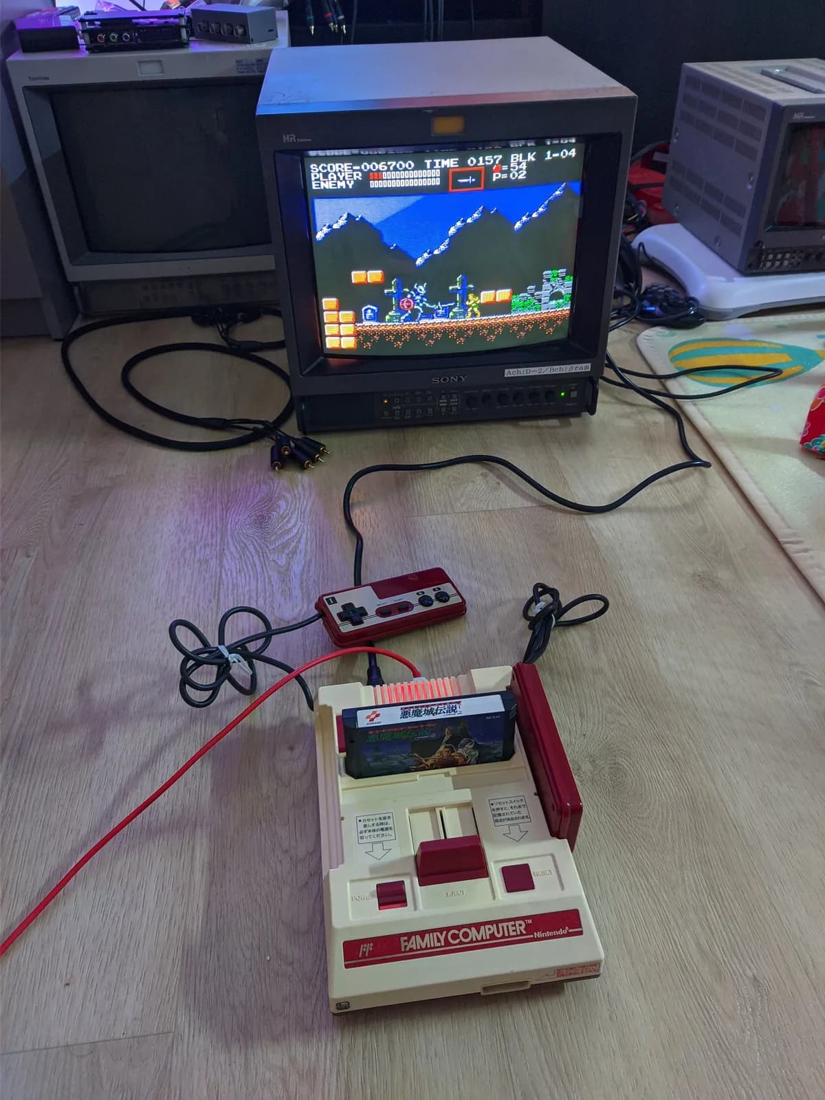 Repaired Nintendo Famicom running Castlevania III on a Sony CRT through its new composite output, with its wired controller and red cartridge in place on the floor.