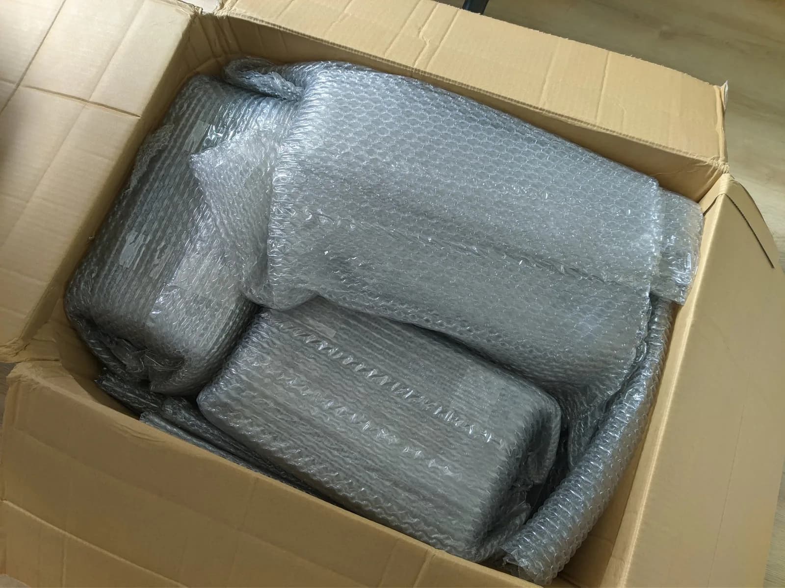 Three Sony PVM-9040 monitors wrapped in bubble wrap inside a cardboard shipping box, showing minimal packaging protection.