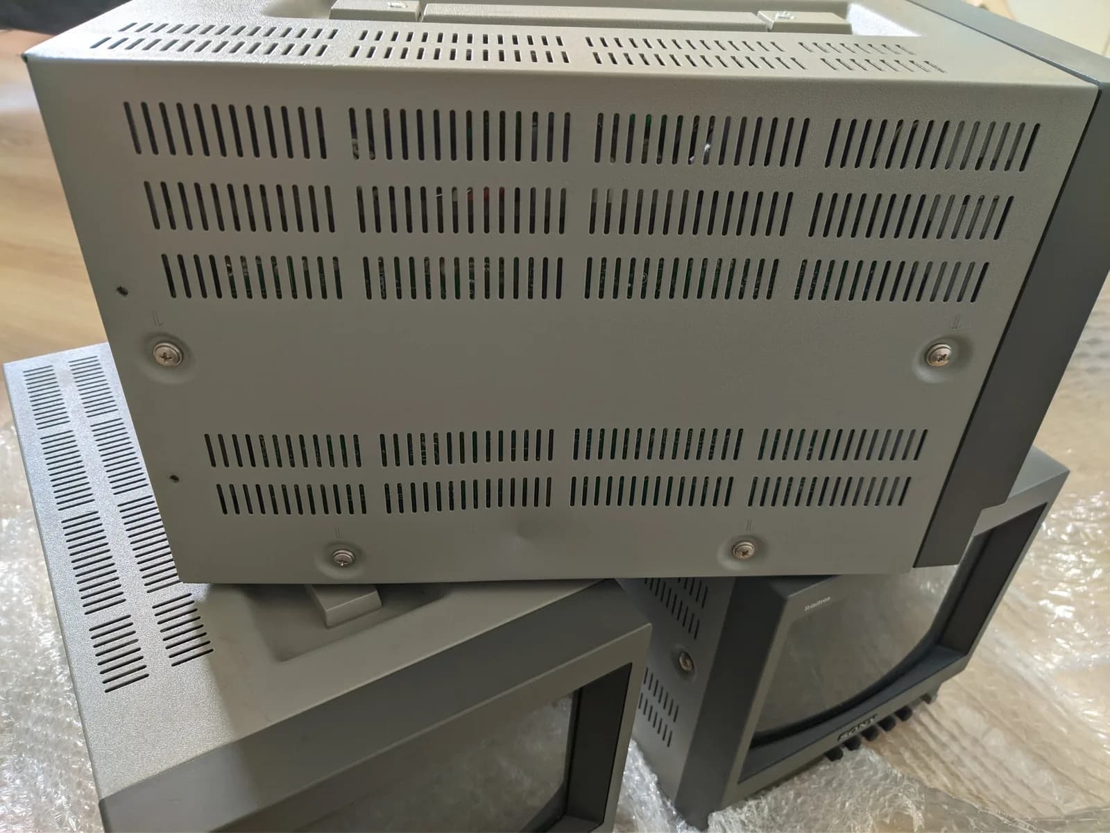Three stacked Sony PVM-9040 CRT monitors showing ventilation grilles and shipping damage to outer casing with visible dent.
