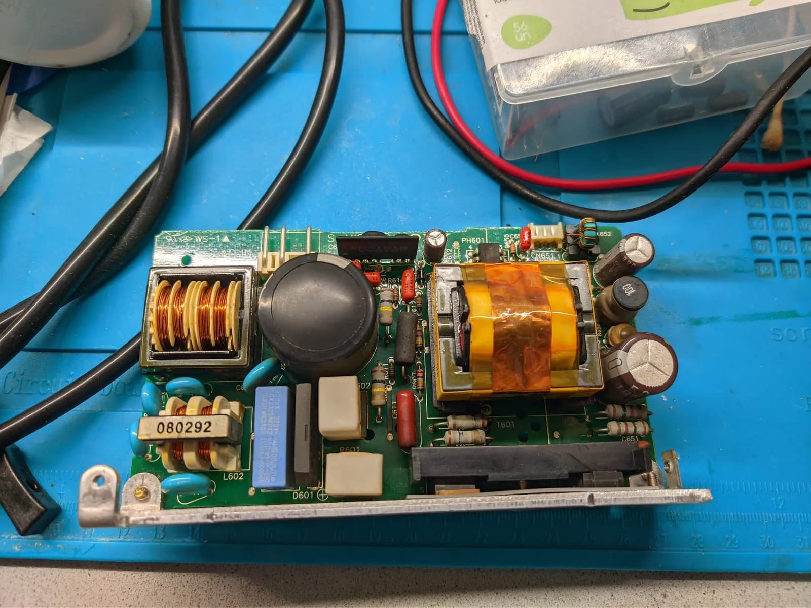 Recapped PSU board from Sony BVM-9045QD showing replaced electrolytic capacitors, transformer, inductor coil, and various resistors on blue work mat.