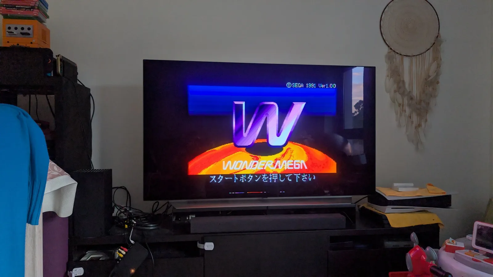 LG C1 OLED TV showing the Sega Wondermega boot screen: the purple "W" WONDERMEGA logo over an orange sunburst, "SEGA 1991 Ver 1.00", and Japanese on-screen text (press start).