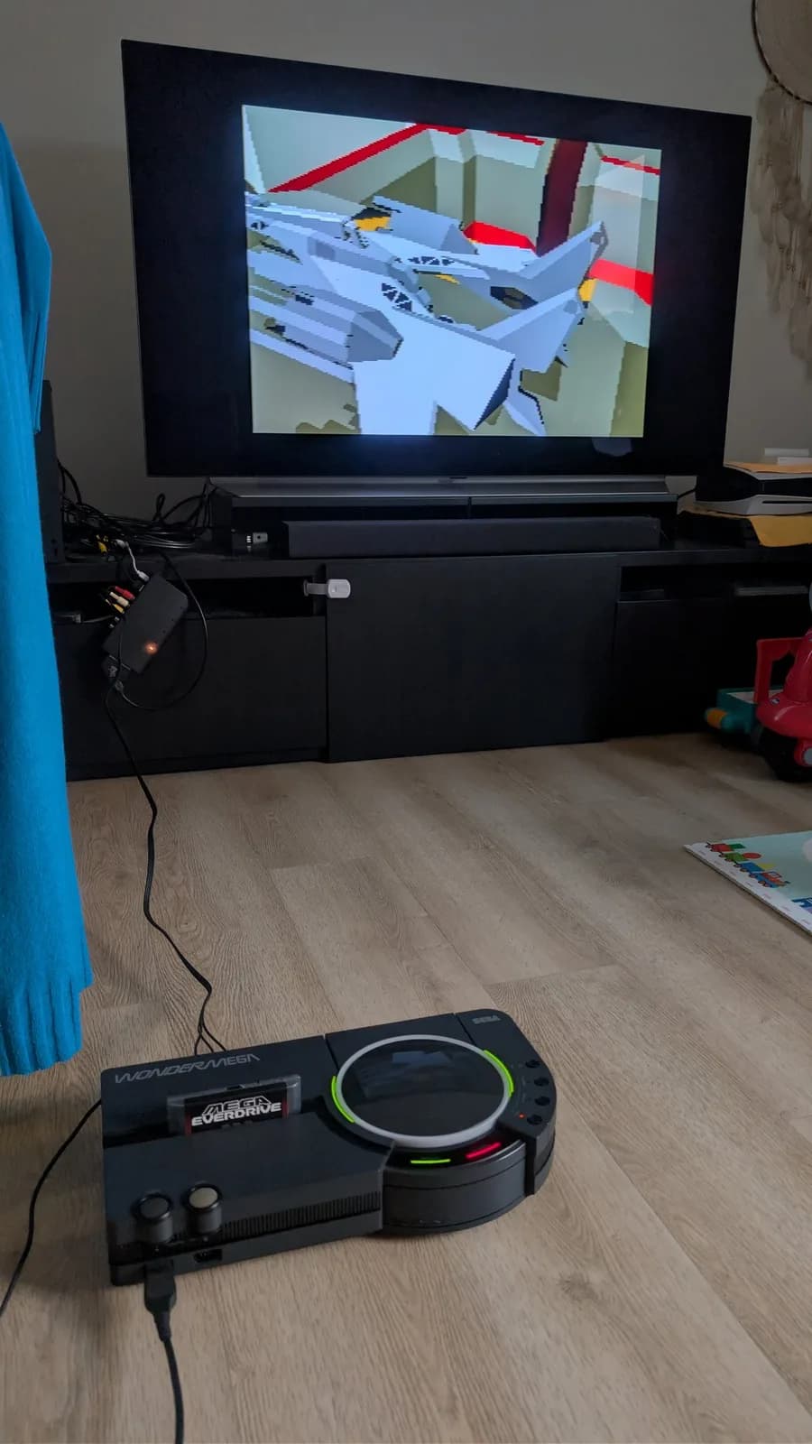 LG C1 OLED TV displaying the 3D-polygon Mega-CD shooter Silpheed, with the restored Sega Wondermega HWM-5010 and its inserted Mega Everdrive Pro cartridge on the floor in the foreground.