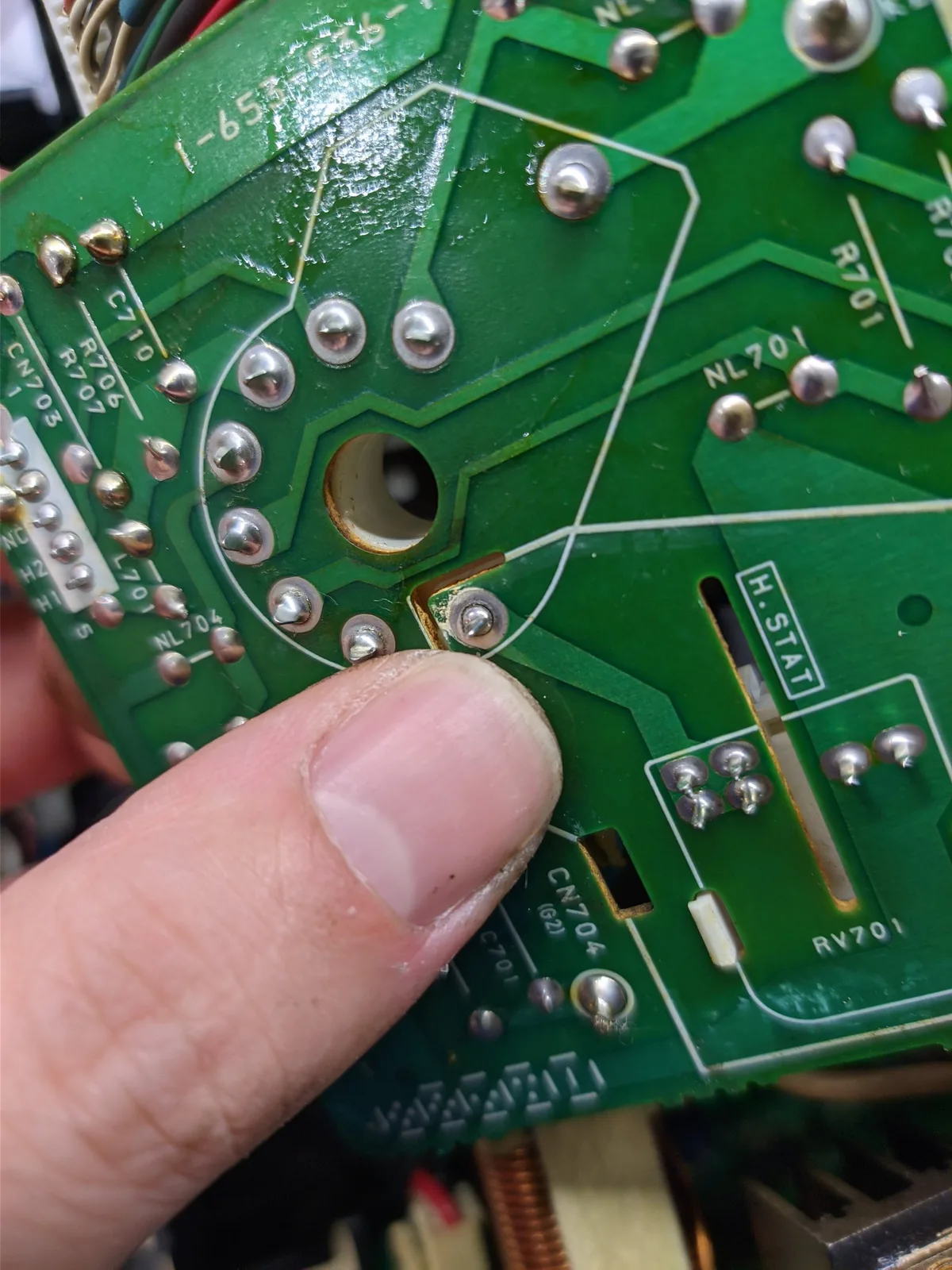 Finger pointing to reflowed solder joint on Sony BVM neckboard, showing repaired connection that caused color loss.