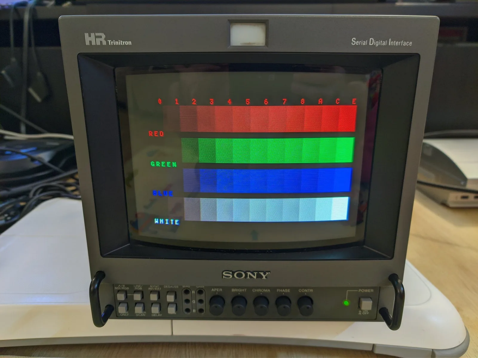 Sony BVM-9045QD displaying color test pattern with RED, GREEN, BLUE, and WHITE bars showing restored vibrant colors after neckboard solder joint repair.