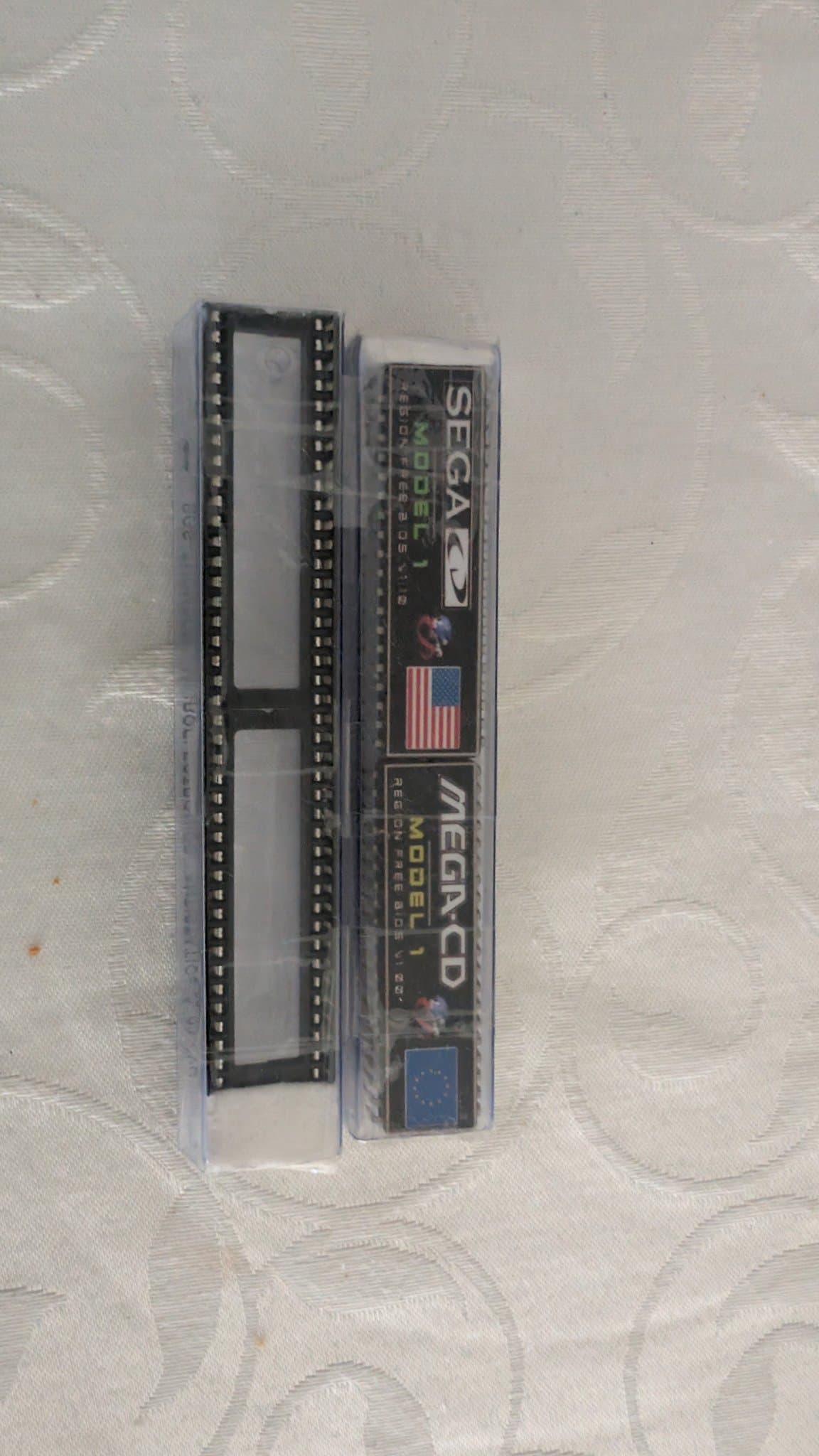 Sega Mega-CD Model 1 unit in clear plastic case showing internal circuit board with dual rows of pin connectors, displayed on textured surface.