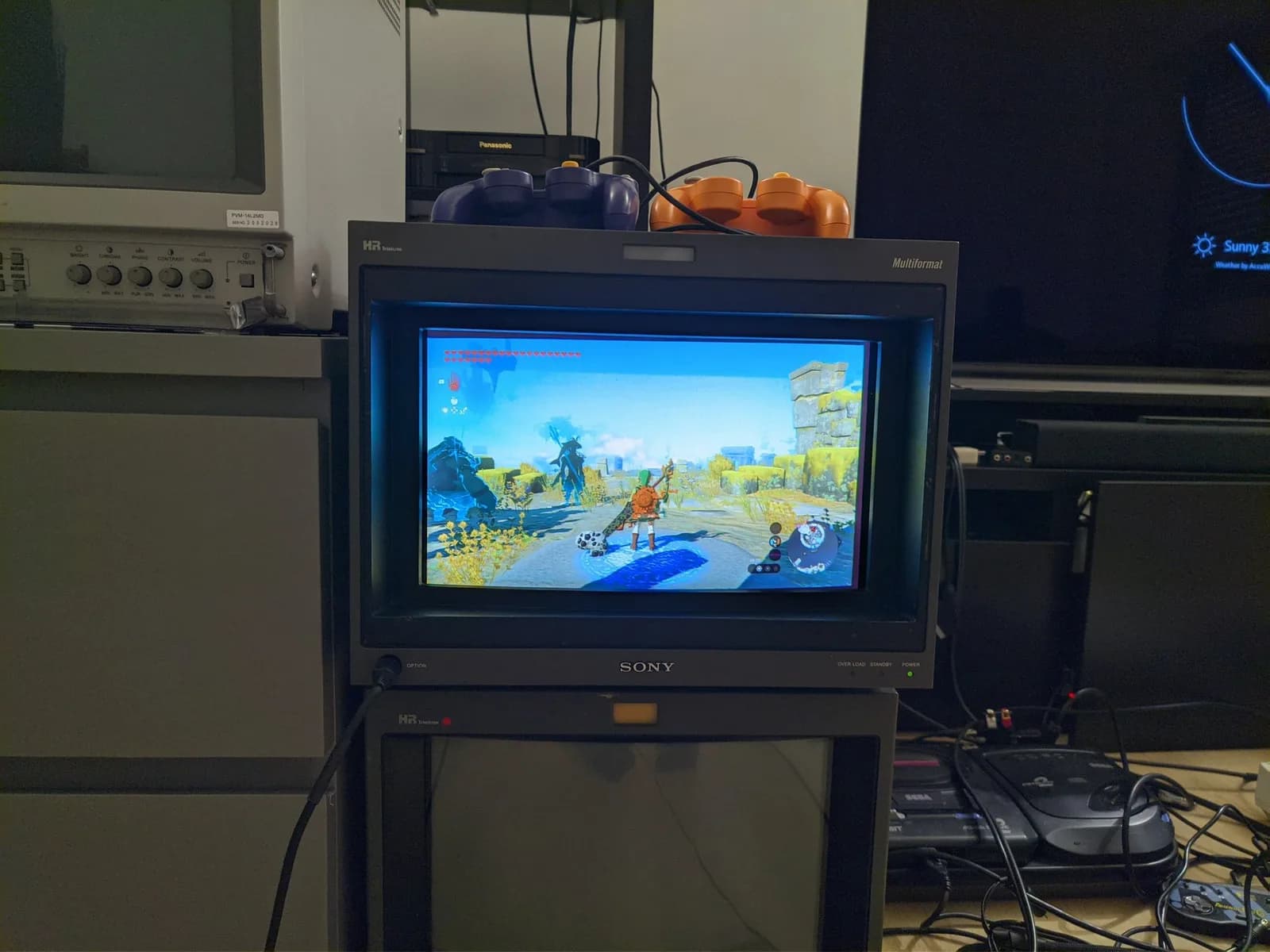 Sony BVM-D14H1E showing The Legend of Zelda: Tears of the Kingdom gameplay (looks like one of the sky islands), a powered-off Sony PVM-14L2MDJ broadcast monitor and control knobs to the left.