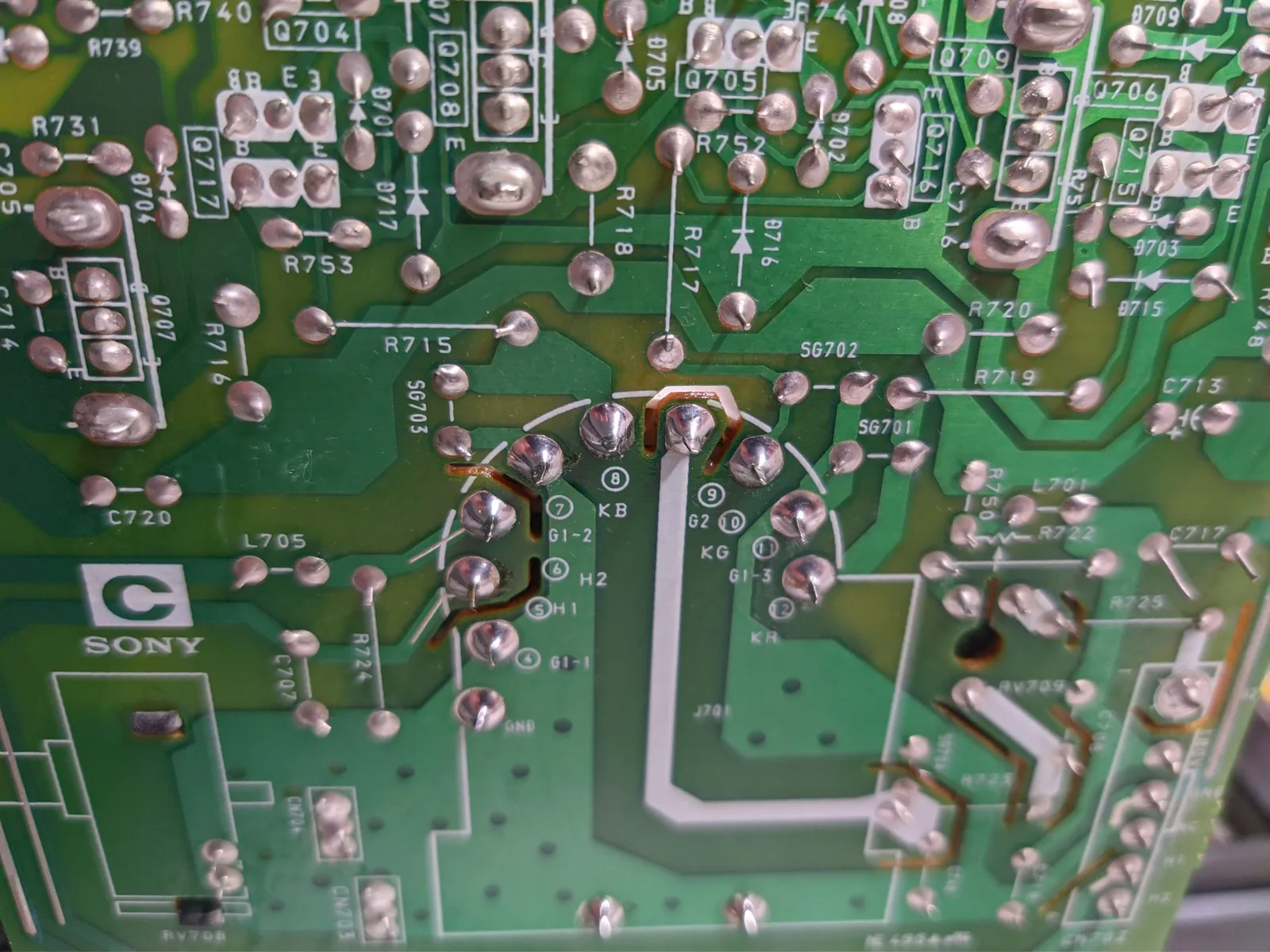 Close-up of Sony PVM-14M4J C board showing broken solder joint at KB tube pin with multimeter probe positioned for diagnosis.