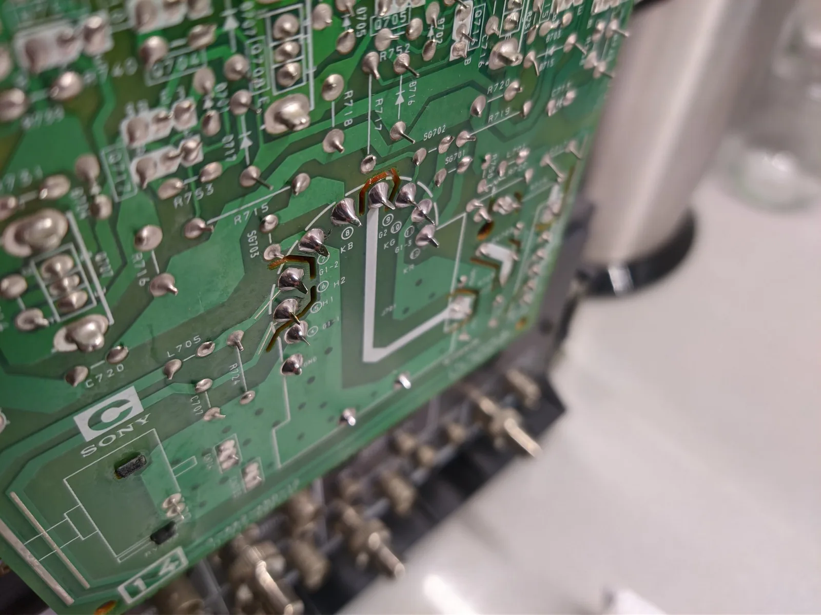 Close-up of Sony PVM-14M4J C board showing broken solder joint at KB tube pin with multimeter probe testing connection.