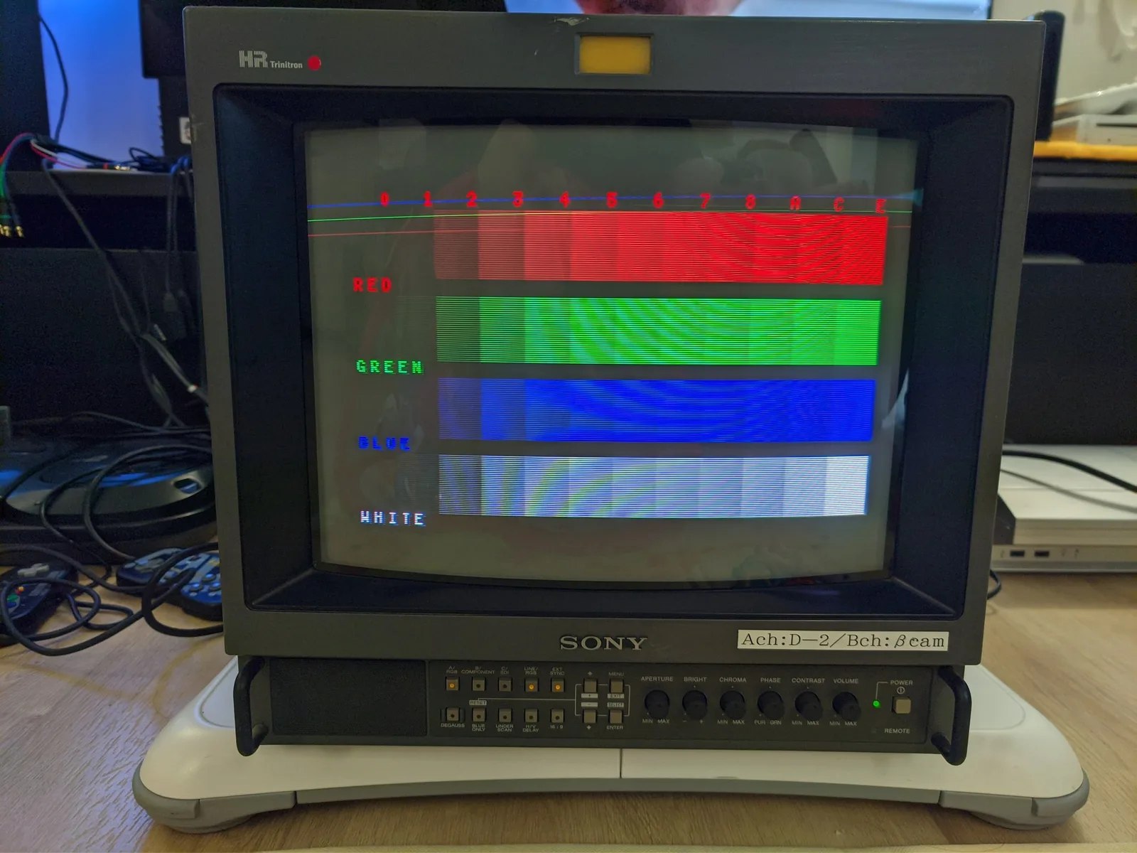 Sony PVM-14M4J displaying color bars test pattern: red, green, blue, and white stripes with numbered scale across top showing successful repair.