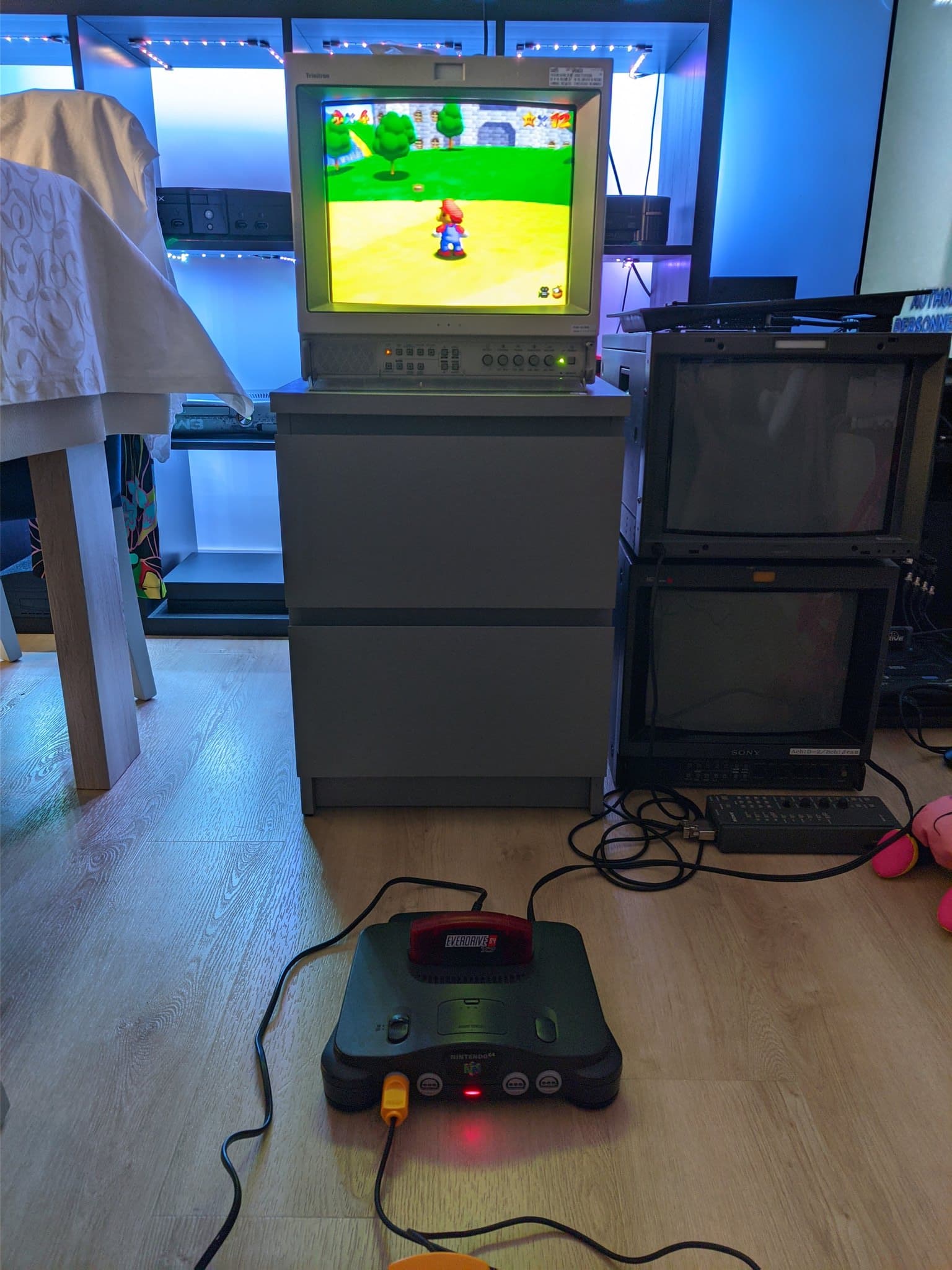 Nintendo 64 connected to a Sony CRT displaying Super Mario 64 gameplay, the top of a controller just visible at the bottom of the shot, testing the console after the recap and service.