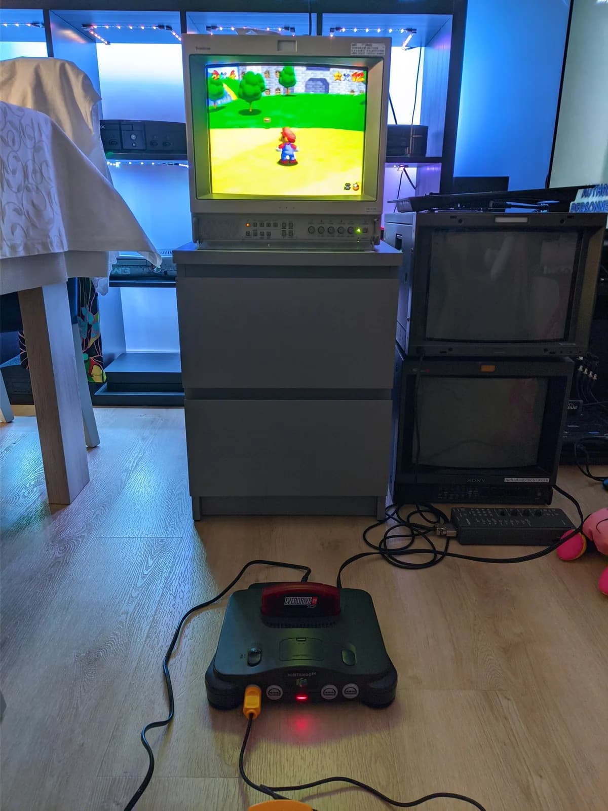 Nintendo 64 connected to a Sony CRT displaying Super Mario 64 gameplay, the top of a controller just visible at the bottom of the shot, testing the console after the recap and service.