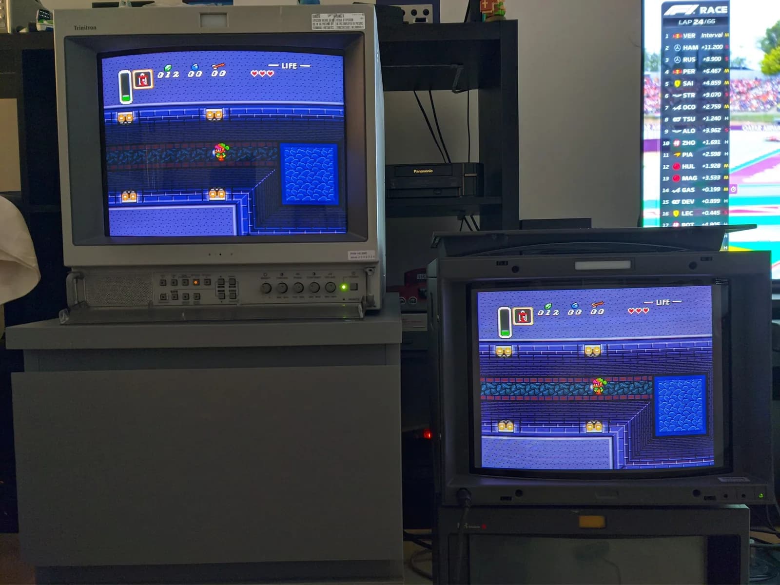 Two Sony Trinitron professional CRT monitors daisy-chained to show the same image, a PVM-14L2MDJ on the left and the BVM-D14H1E on the right, both displaying The Legend of Zelda: A Link to the Past (Link in a top-down dungeon with a LIFE hearts meter).