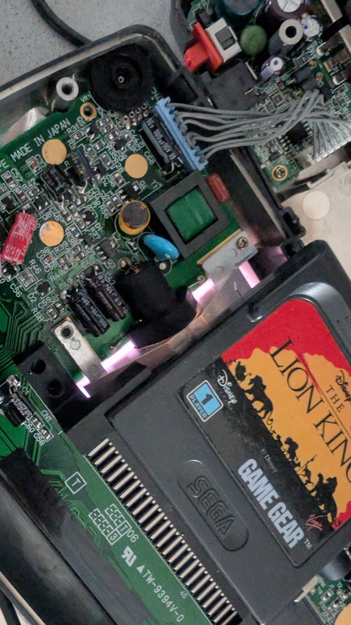 Game Gear motherboard with exposed CCFL backlight assembly and internal components during bulb replacement repair.