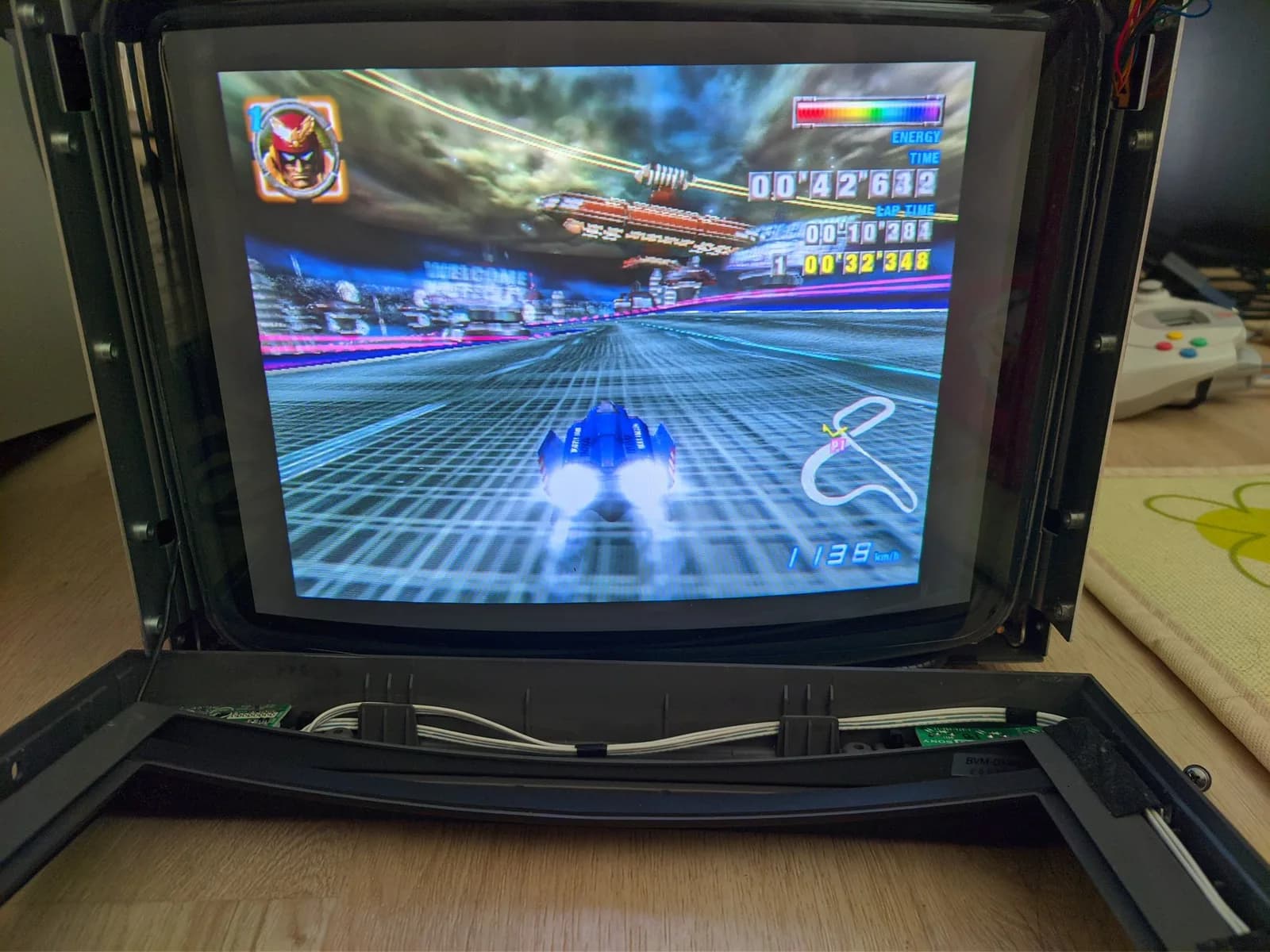 Sony BVM-D14H1E showing F-Zero GX gameplay at 480p (Captain Falcon in a blue machine, the on-screen energy, time and speed readouts), the monitor's front fascia removed and resting in front of the tube.