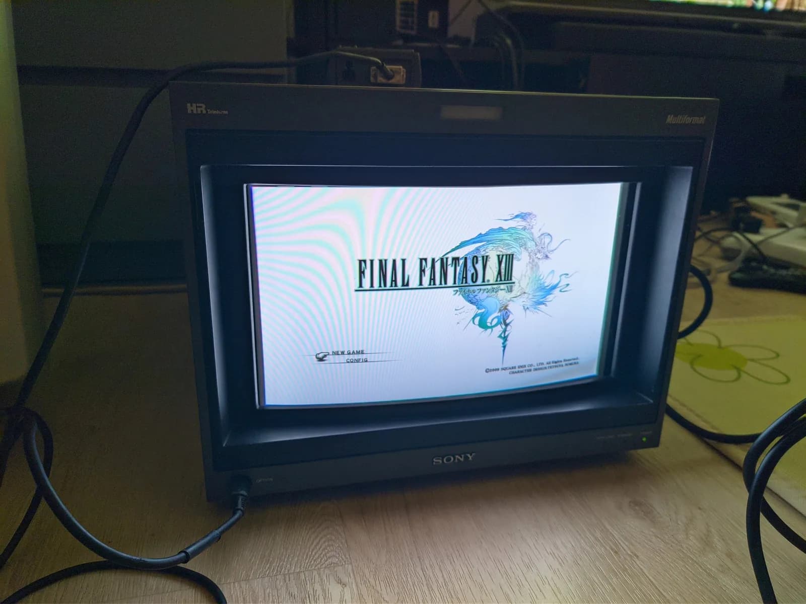 Final Fantasy XIII title screen (NEW GAME and CONFIG menu) on the Sony BVM-D14H1E, over a solid white background (the faint blue banding is photographic moire, not on the screen).