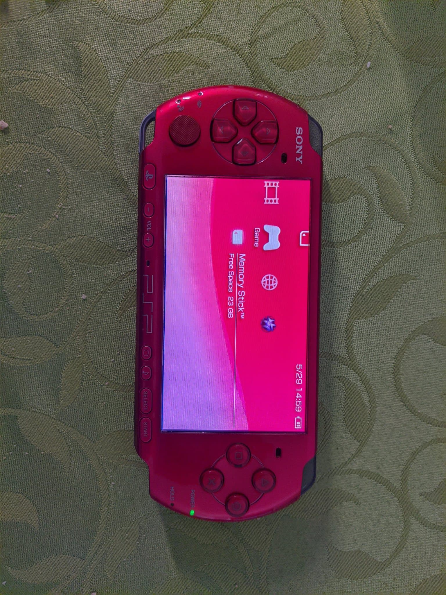 Red Sony PSP-3000 displaying memory stick menu on screen, showing 5:29/14:59 time stamp during battery replacement repair work.