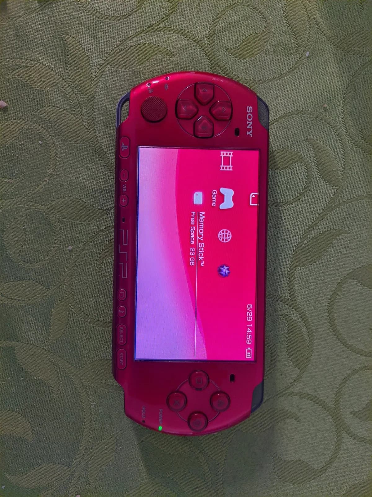 Red Sony PSP-3000 displaying memory stick menu on screen, showing 5:29/14:59 time stamp during battery replacement repair work.