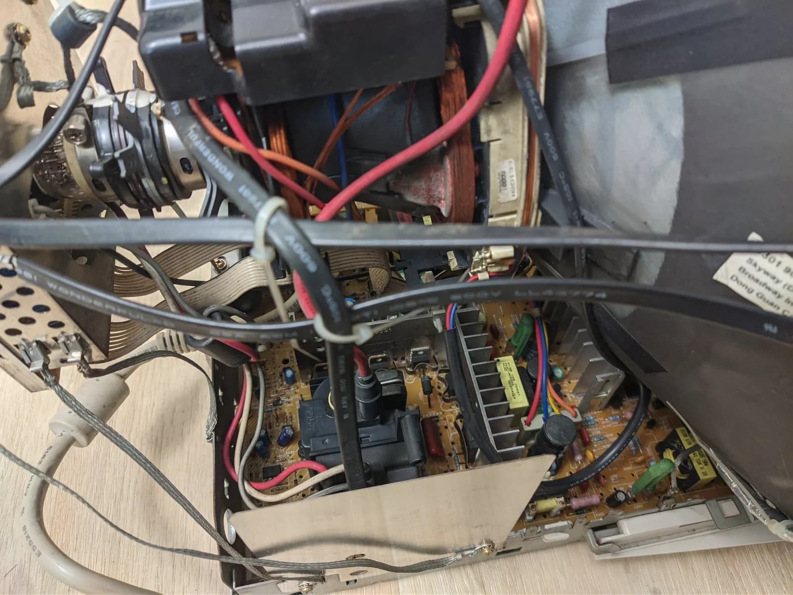 Interior of the Philips 109S4 showing the power-supply board (a silver heat sink, green and blue electrolytics) with the tube neck, a copper coil and wiring above.