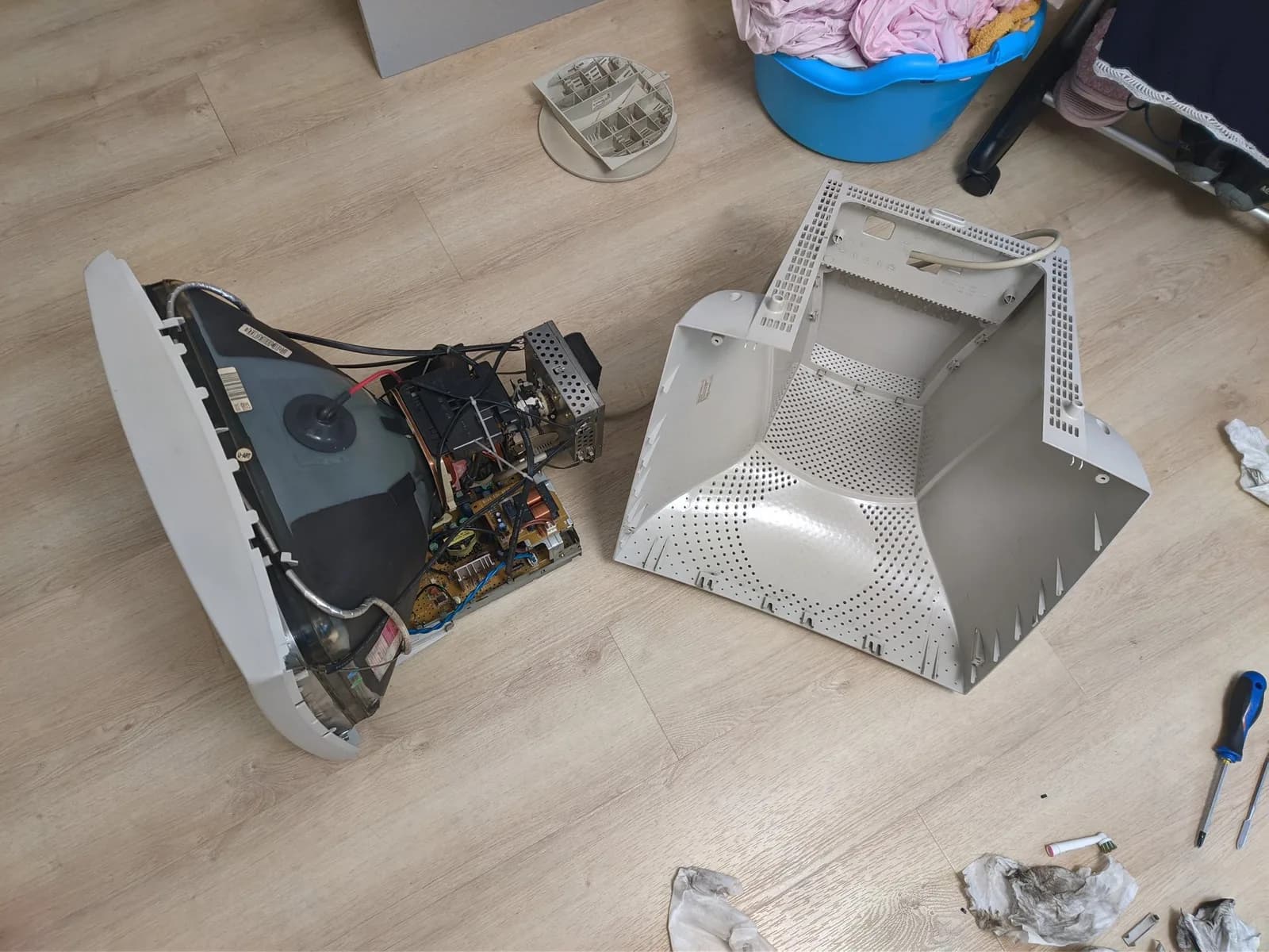 The cleaned Philips 109S4, fully deshelled (tube, chassis and boards) on the floor beside its removed beige rear shell, both now noticeably cleaner including the inside of the shell that fits over the back of the monitor, with screwdrivers, an electric toothbrush and used cleaning wipes nearby.
