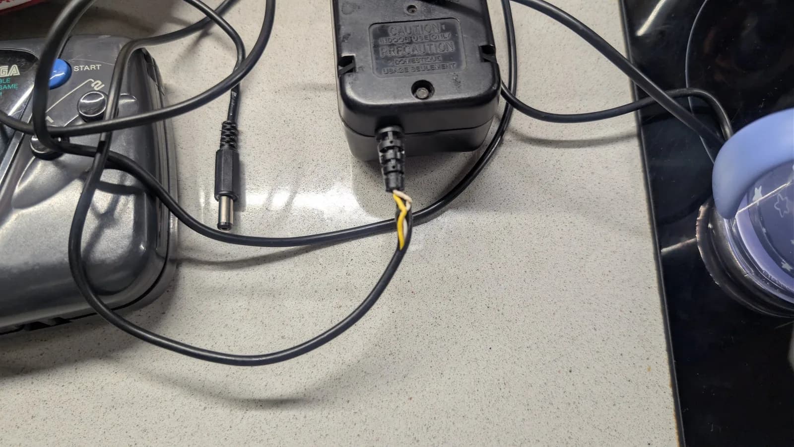Game Gear power connector with newly soldered wires wrapped in layered heat shrink tubing, demonstrating strain relief repair technique.