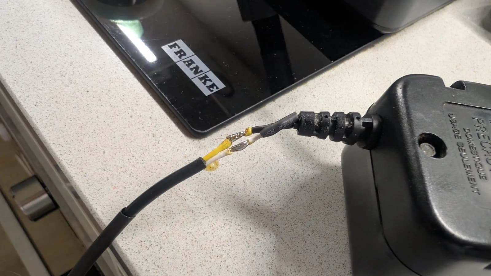 Close-up of repaired Game Gear power cable with heat shrink tubing layers around soldered wire connections and strain relief.