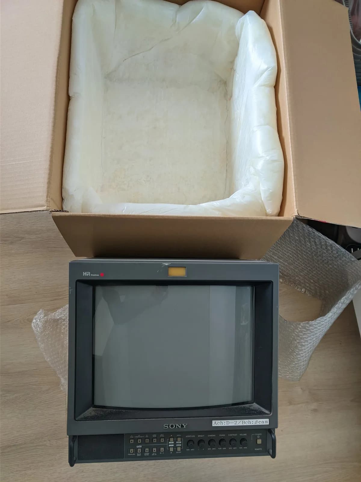 Sony PVM-14M4J CRT monitor unboxed with protective plastic wrap, showing gray casing and control panel before repair work begins.