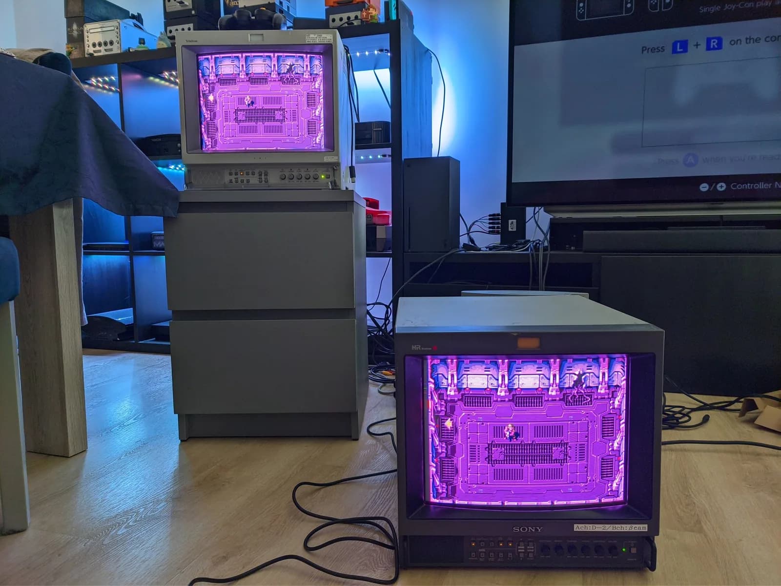 Sony PVM-14M4J displaying magenta test pattern with retrace lines visible; second PVM in background shows same pattern for comparison testing.