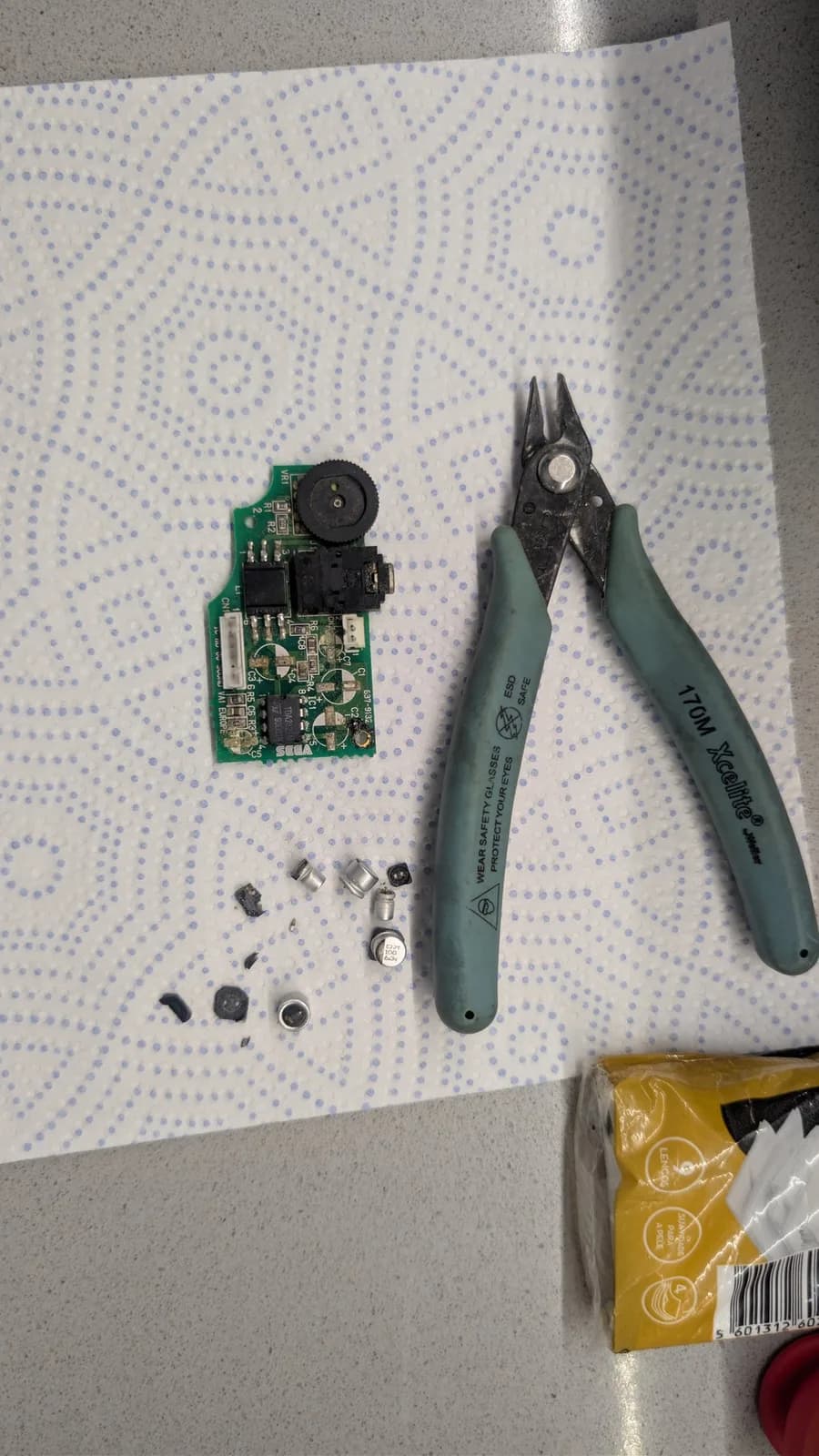 Disassembled Game Gear power board with broken solder joints, Wiha pliers, and loose components after vinegar cleaning process.