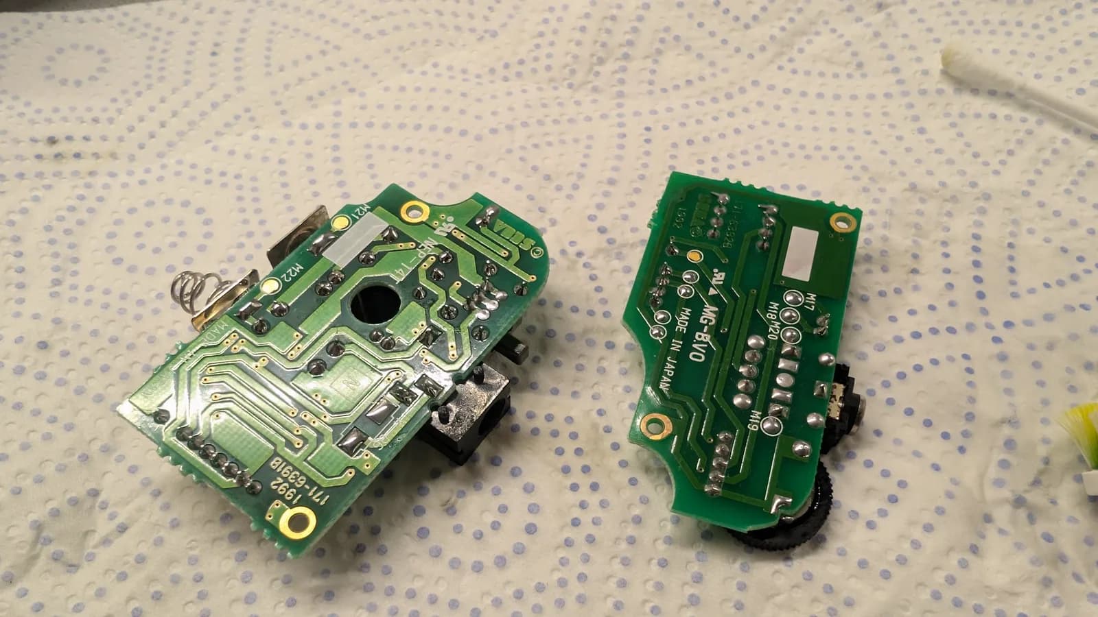 Two Game Gear circuit boards after recapping and solder reflow repair work, displayed on dotted surface.