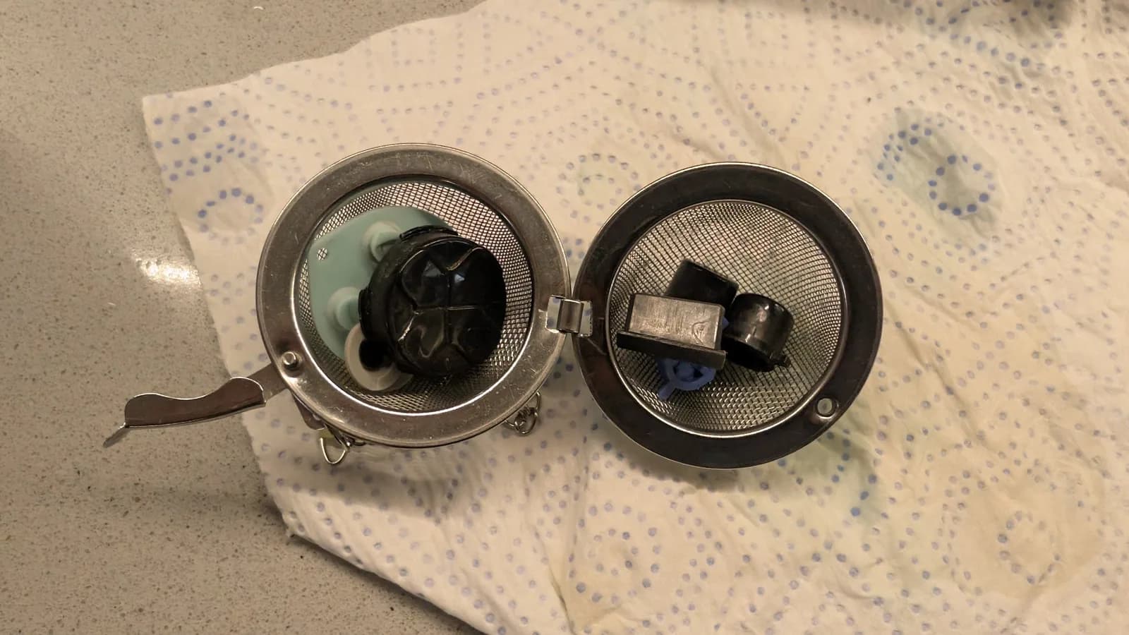 Two disassembled Sega Game Gear speaker domes on paper towel, left showing internal components, right displaying replacement speaker unit.