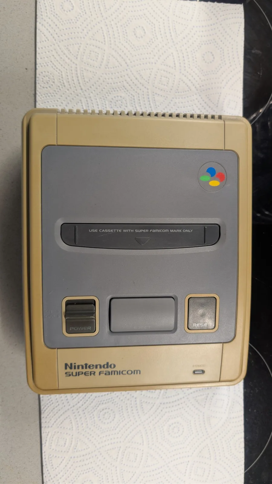 Yellowed Nintendo Super Famicom console showing discolored tan shell with gray faceplate, cassette slot, and control buttons before restoration work.