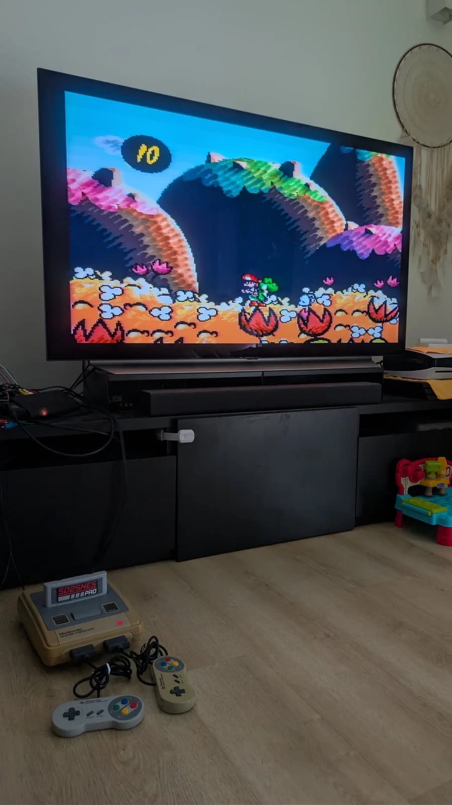 Super Famicom console displaying Yoshi's Island on TV during smoke test; controllers and console visible on desk below screen.