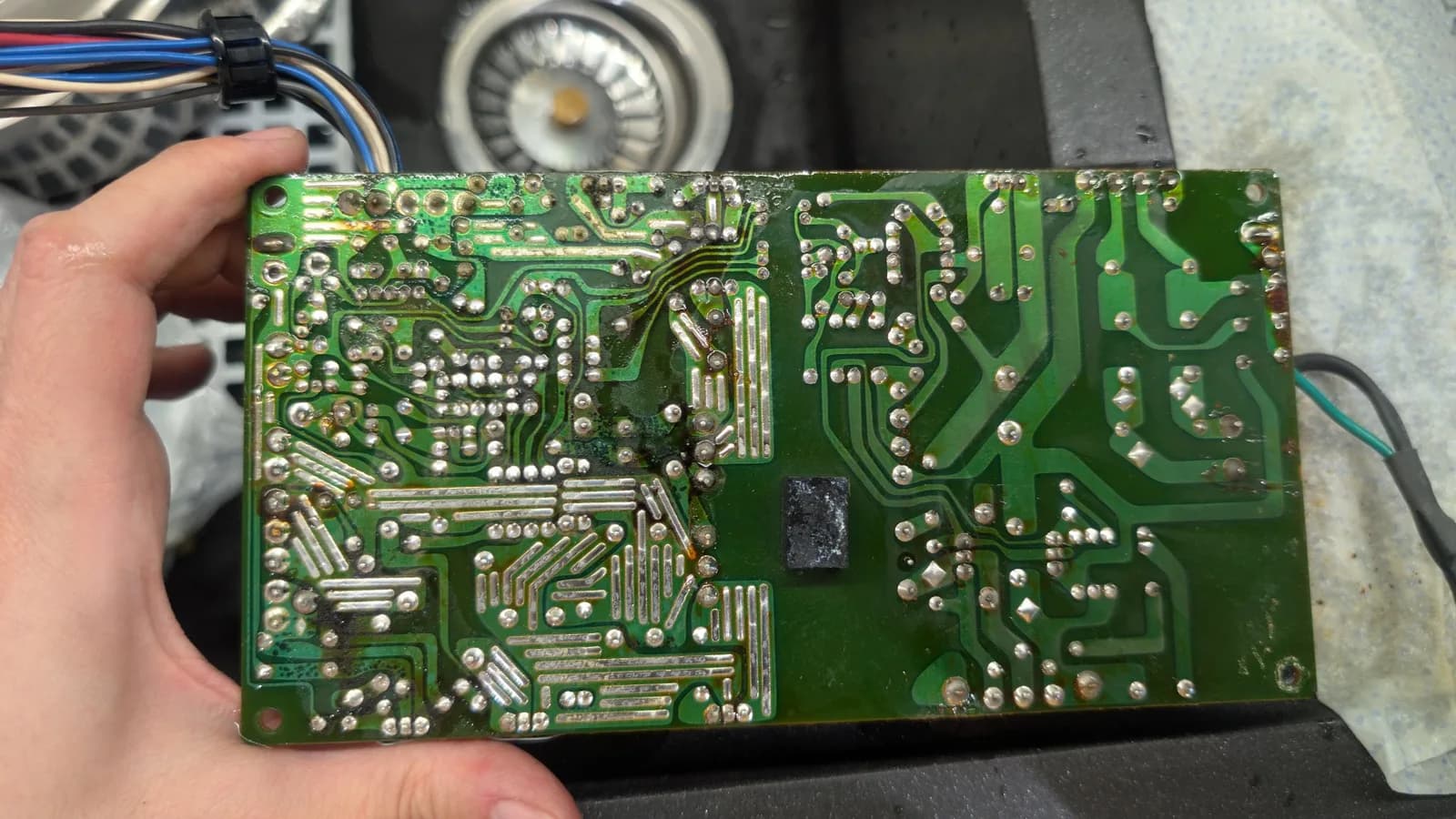 The underside of the Sharp X68000 PSU PCB, showing extensive corrosion and electrolyte damage to the solder mask, the solder joints and the traces.