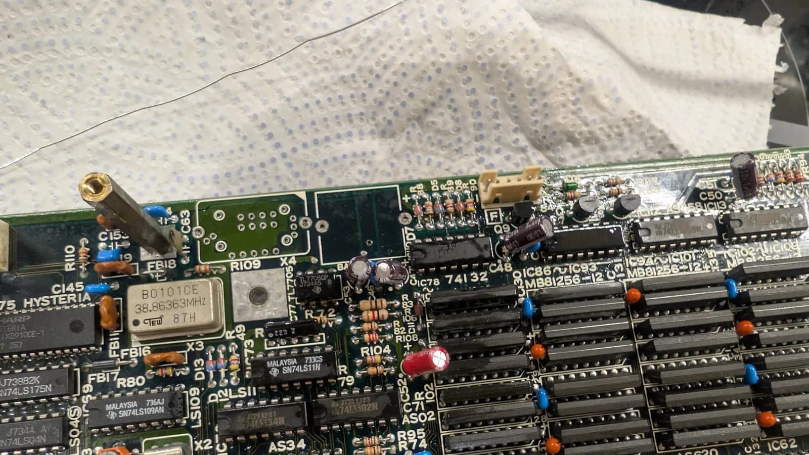 Close-up of the topside of the Sharp X68000 main board before the new battery and oscillator went in, the surrounding components' solder joints shiny and fluxed after a reflow to remove the contamination.