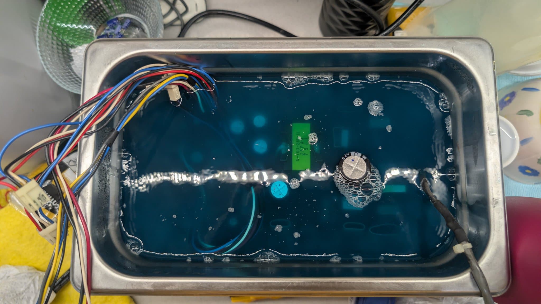 Sharp X68000 PSU capacitor measurement showing failed component; multicolored wires and silver cylindrical capacitor visible in metal enclosure.
