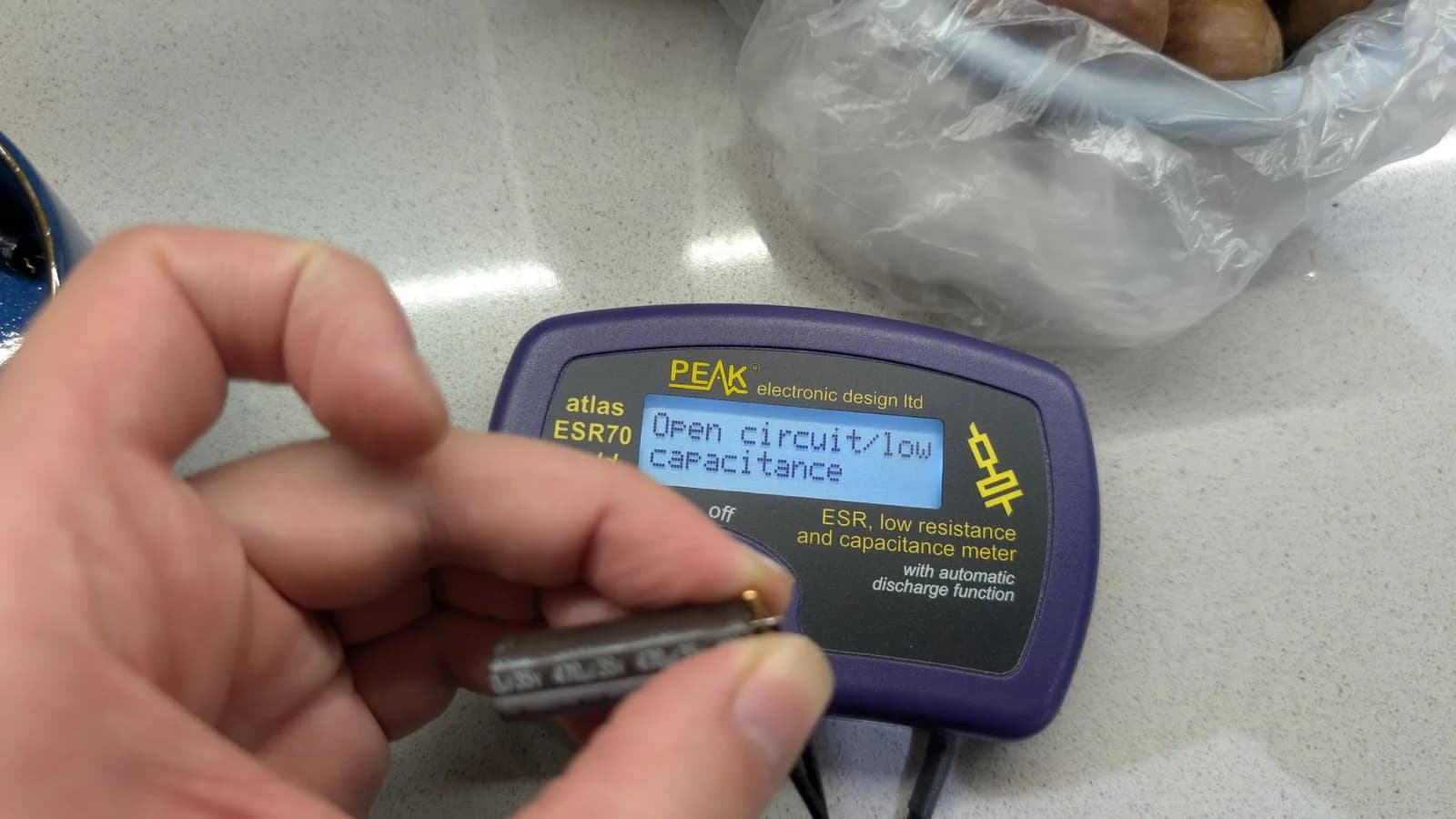 Close-up of the PEAK Atlas ESR70 meter showing "Open circuit / low capacitance" during the Sharp X68000 PSU capacitor testing.