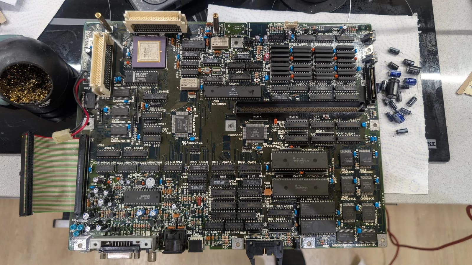 The recapped Sharp X68000 main board, its ICs and RAM cleaned, the old removed capacitors off to its right side; the oscillator and battery mod not yet installed at this stage.