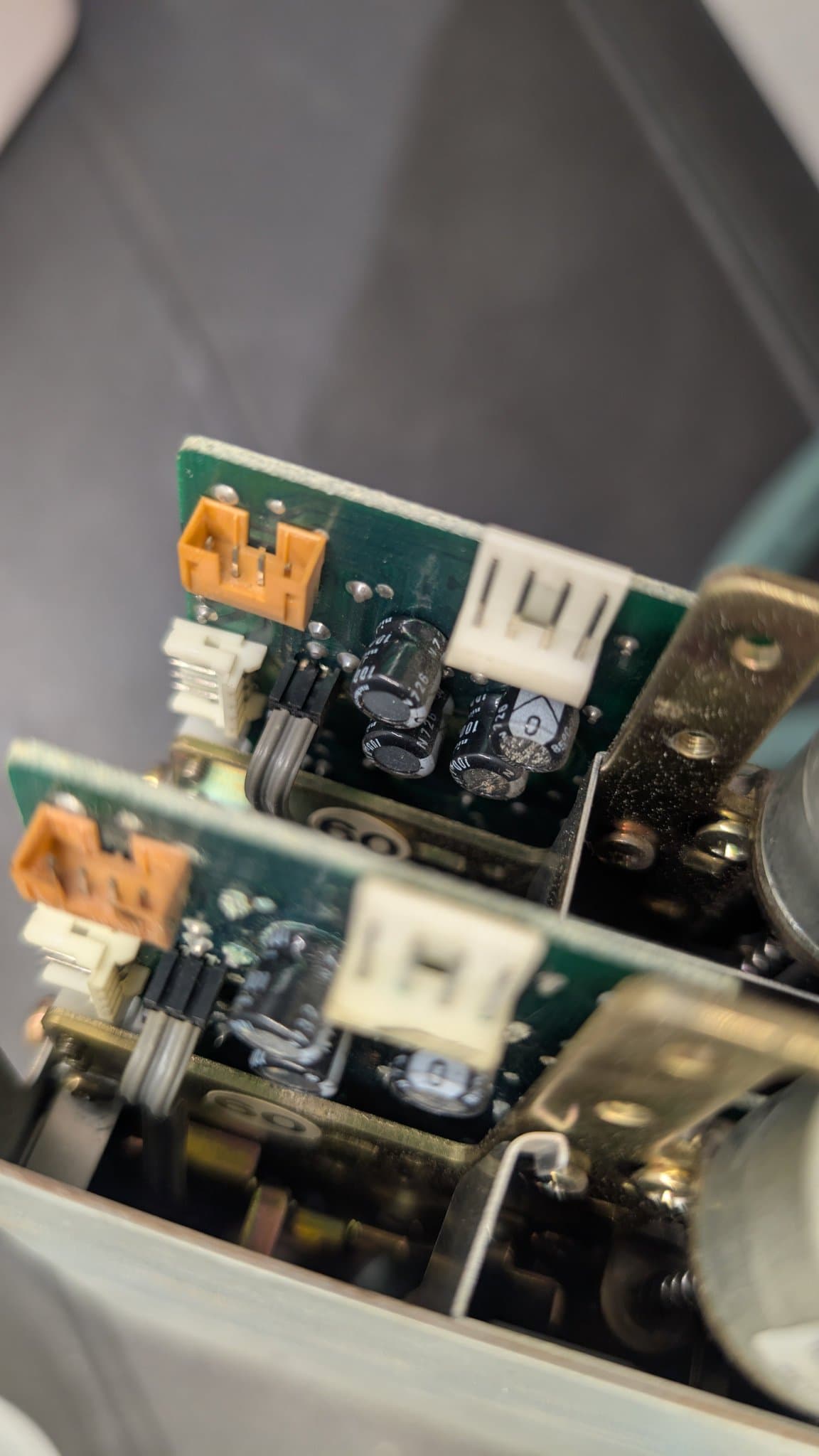 Two stacked green PCBs with orange connectors showing internal components; upper board has 4 capacitors, lower has 3, displaying capacitor damage aftermath.