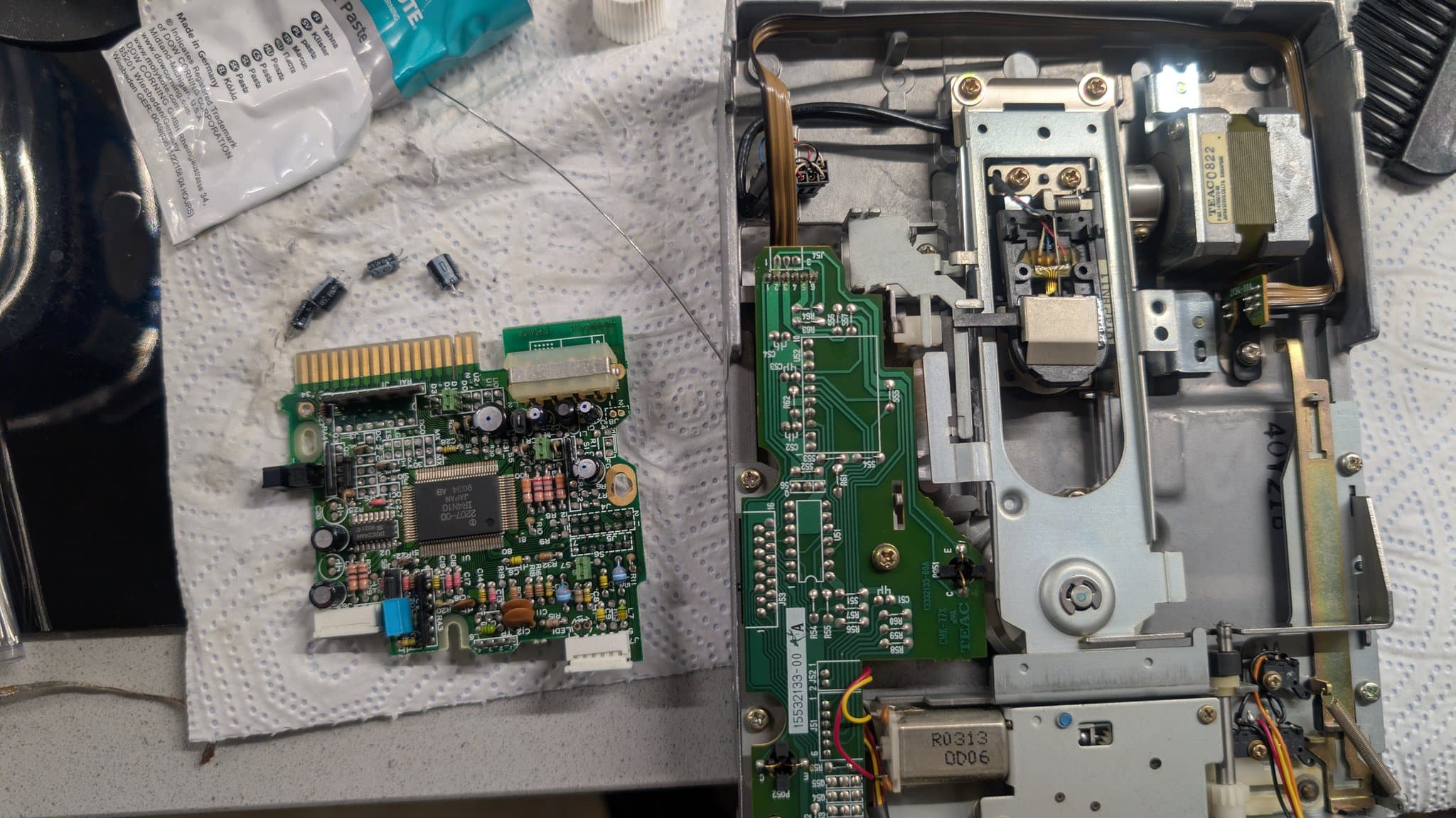 Another recapped floppy drive controller board from the Sharp X68000 Pro II beside its cleaned metal housing, the drive head cleaned and the moving parts relubricated.