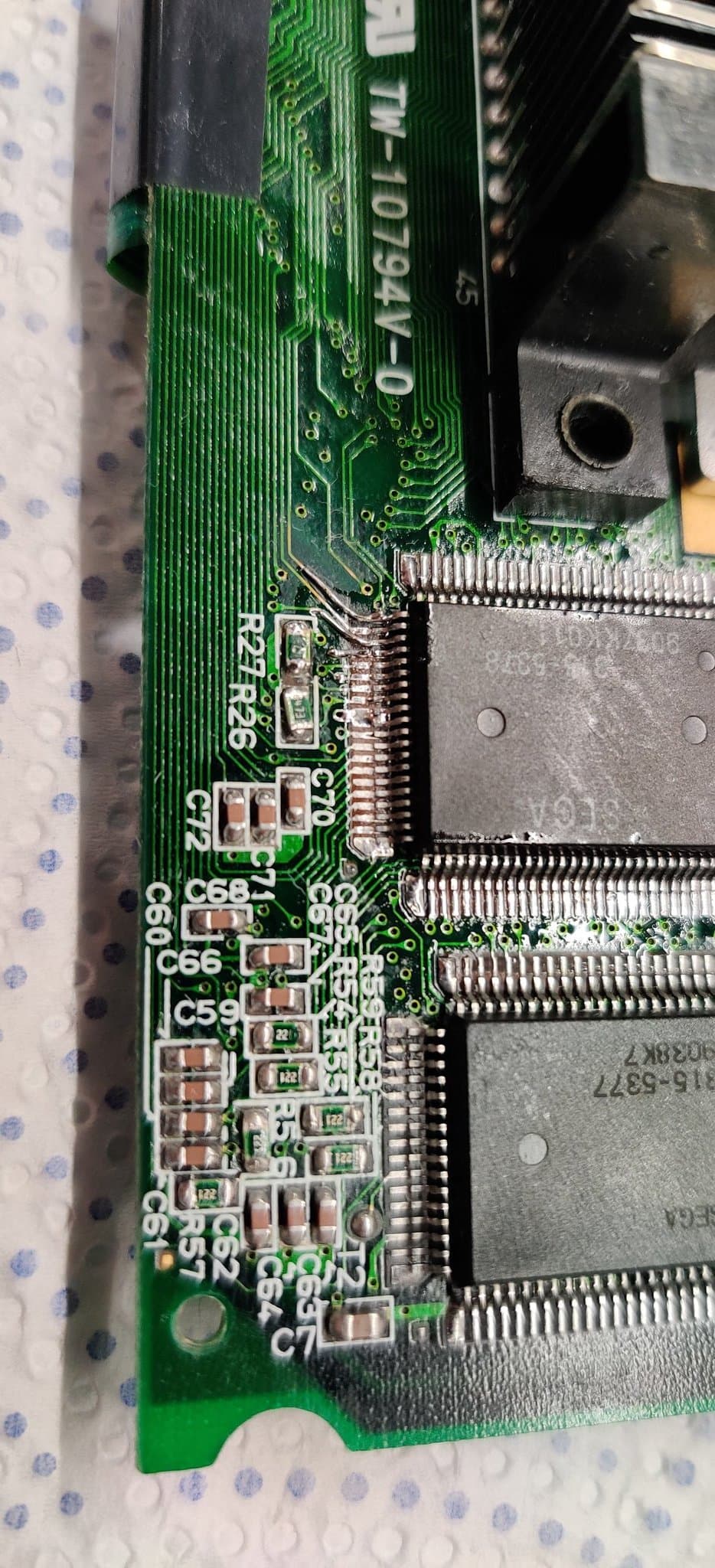 Close-up of a Game Gear board during the later sound repair, with the corroded solder joints reworked around the capacitors and the two large ASICs of this twin-ASIC unit, the VDP and the SCA.