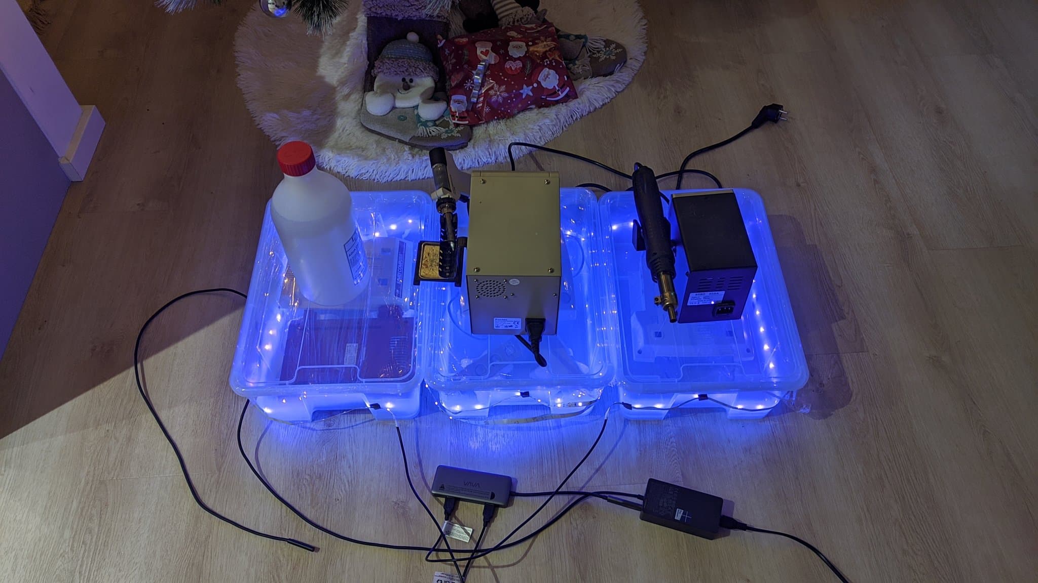 Famicom motherboard with composite mod board installed, seated in illuminated repair workstation with power supplies and testing equipment connected.