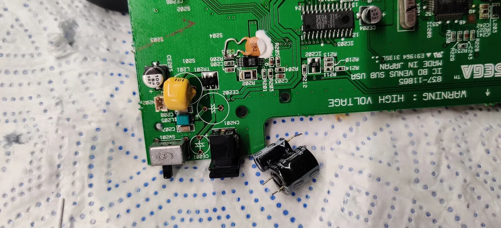 Sega Nomad motherboard showing replaced capacitors, cleaned solder joints around power section, and refurbished power jack during restoration.