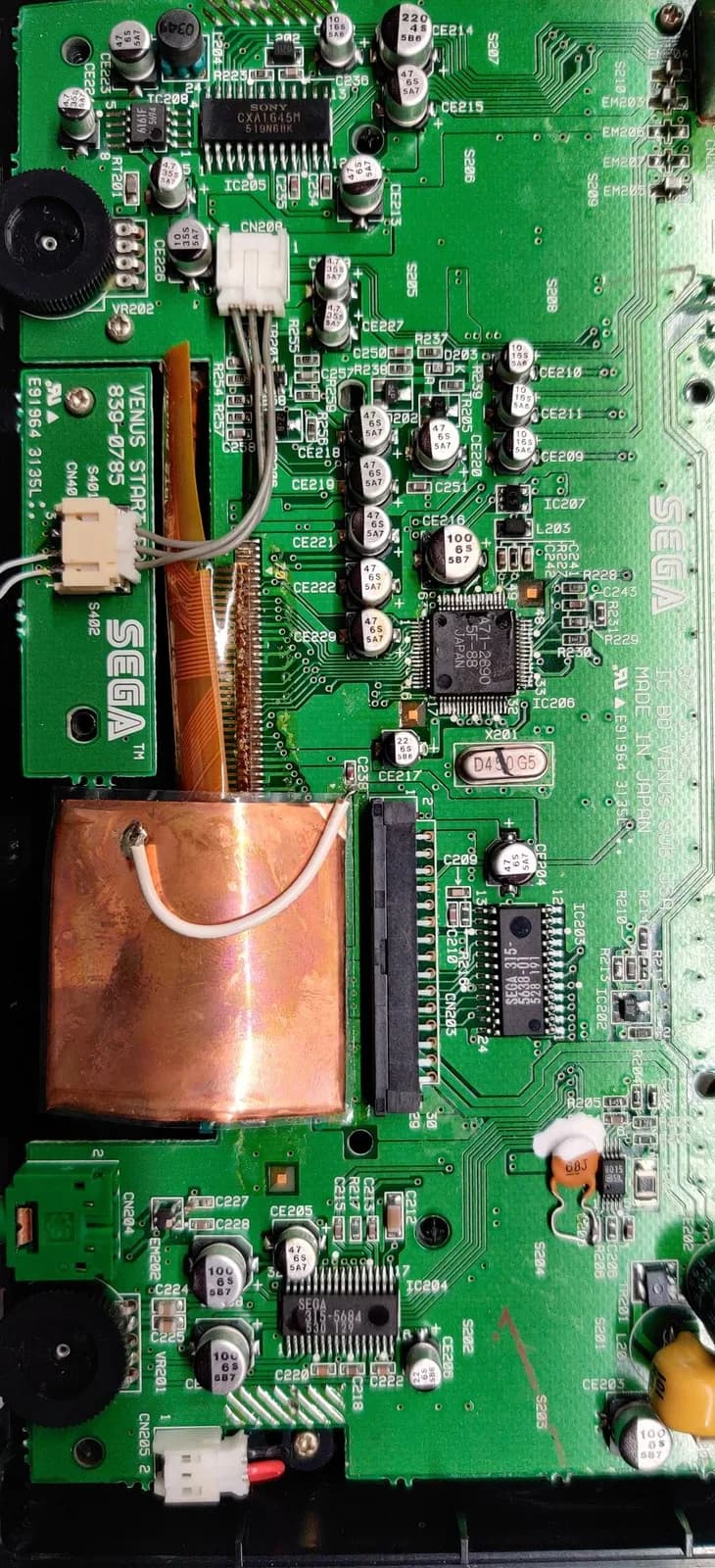 Sega Nomad motherboard showing copper heatsink, capacitors, and IC chips with visible solder joints during restoration work.