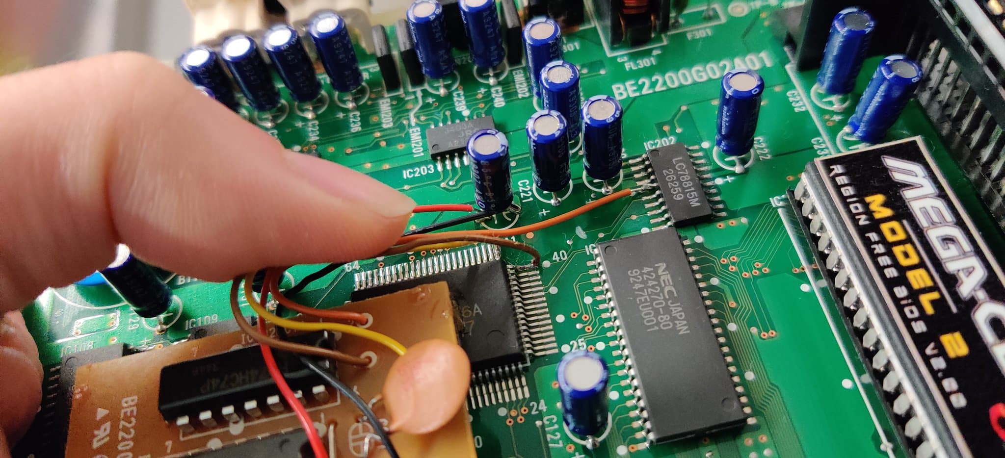 Sega Mega-CD 2 circuit board showing the factory bodge wires soldered to capacitors and ICs, during restoration inspection.