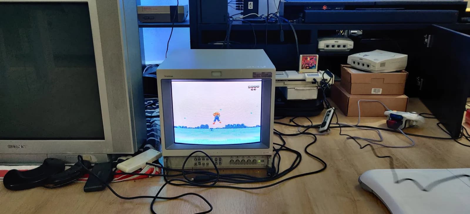 A Sony PVM-14L2 broadcast monitor running Space Harrier 3D with the shutter glasses draped over it, and a beige Sega Mark III beside it with the Space Harrier 3D cartridge in its slot, a Dreamcast and boxes to the right.