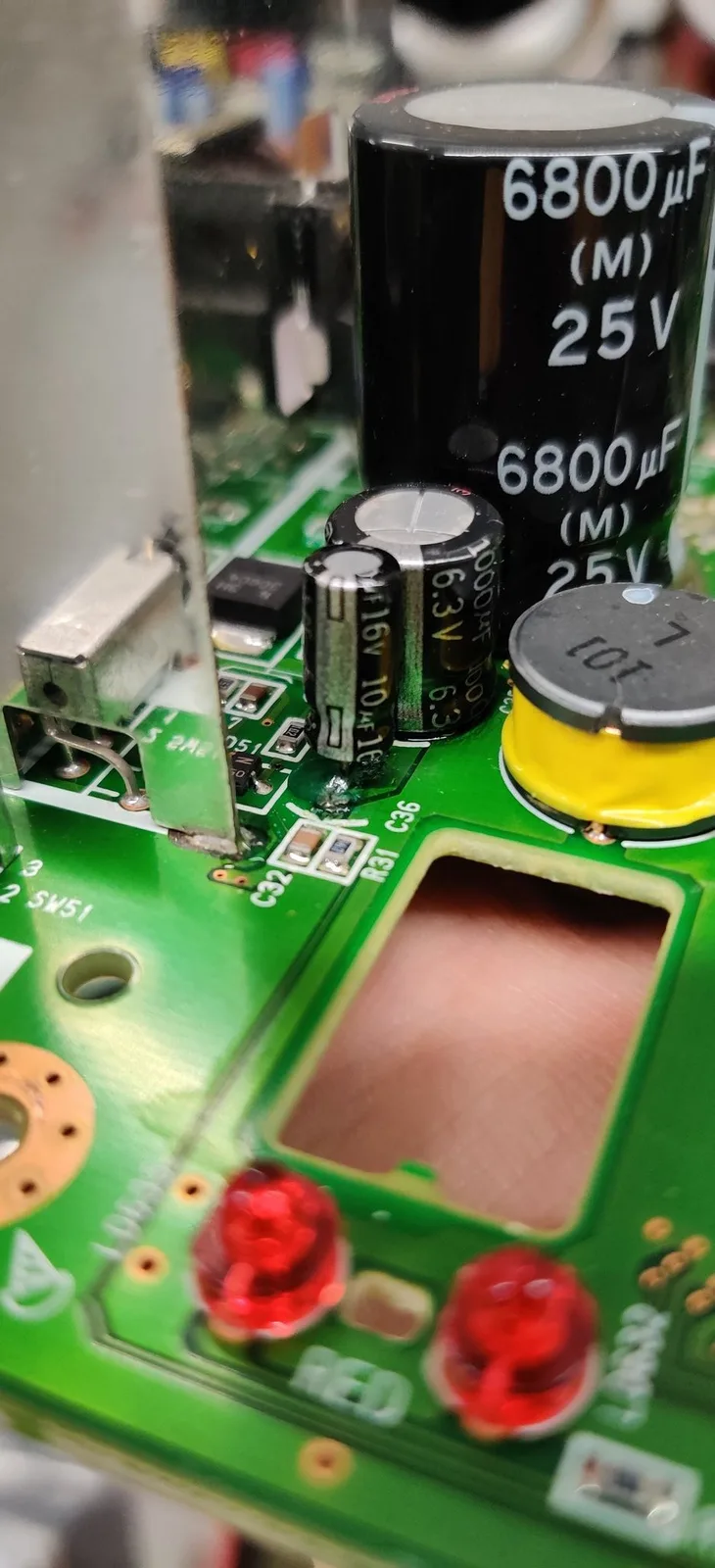 Panasonic FZ-1 PSU board showing 6800µF 25V capacitors, damaged traces, and rework solder joints during restoration.