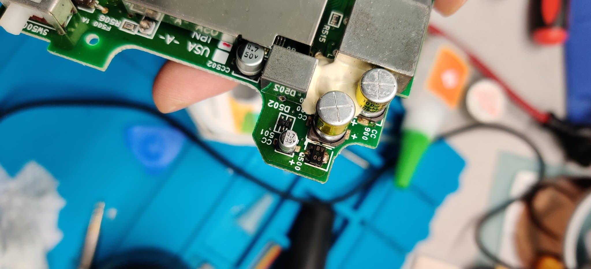 Leaked capacitors on the NEC PC Engine GT mainboard, the worst-affected area, with corrosion visible on the capacitor pads and around Q500 from the electrolyte leakage (every cap on the unit had leaked).