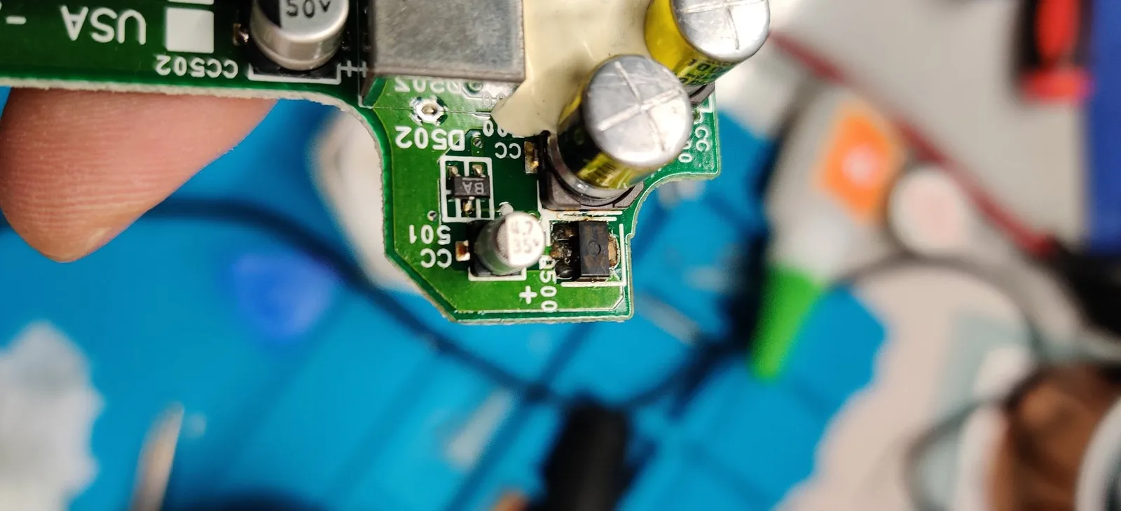 A tighter shot of the same PC Engine GT mainboard area around Q500, the heavy brownish electrolyte residue from the leaked capacitors clearly visible.