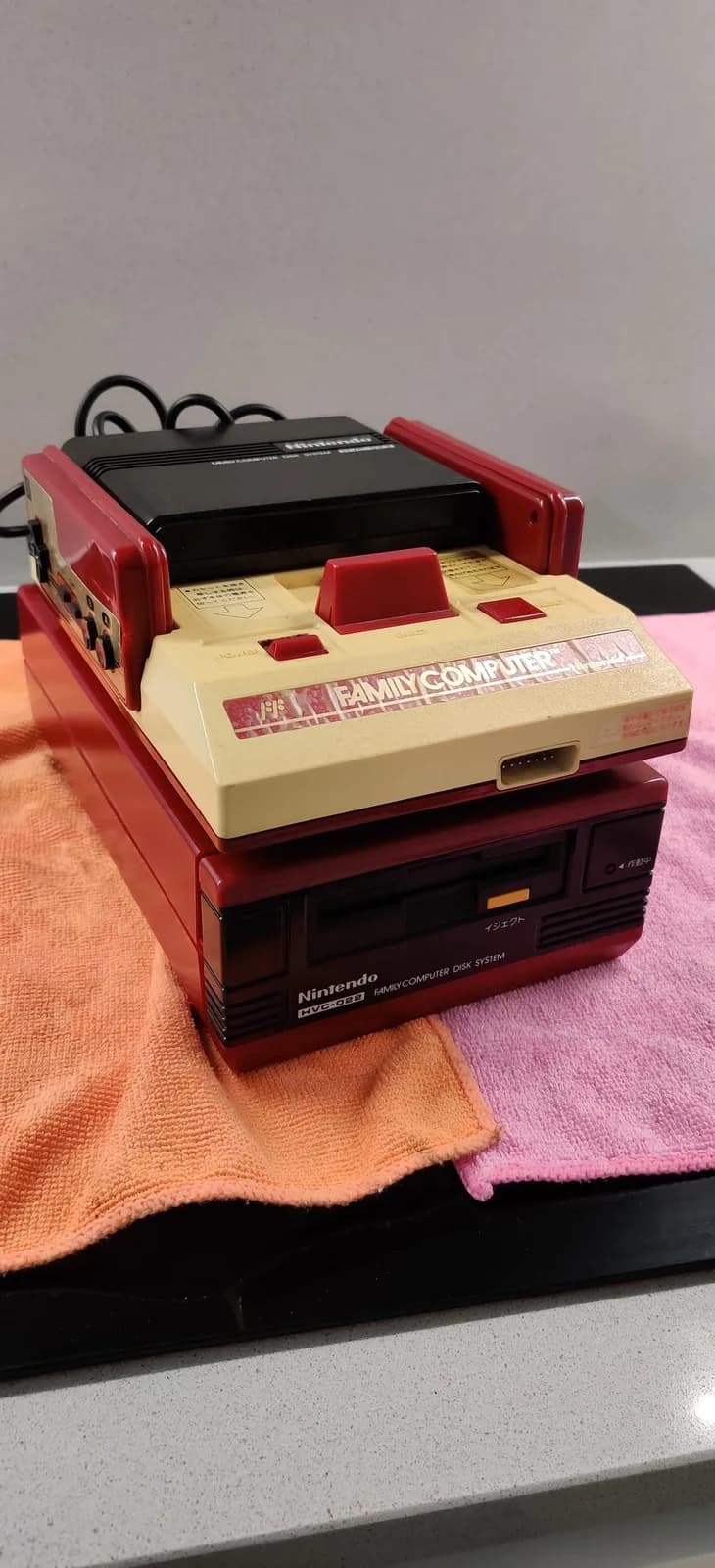 Red and cream Nintendo Famicom with composite mod board installed, displayed with replacement fuse and cleaning cloth during repair documentation.